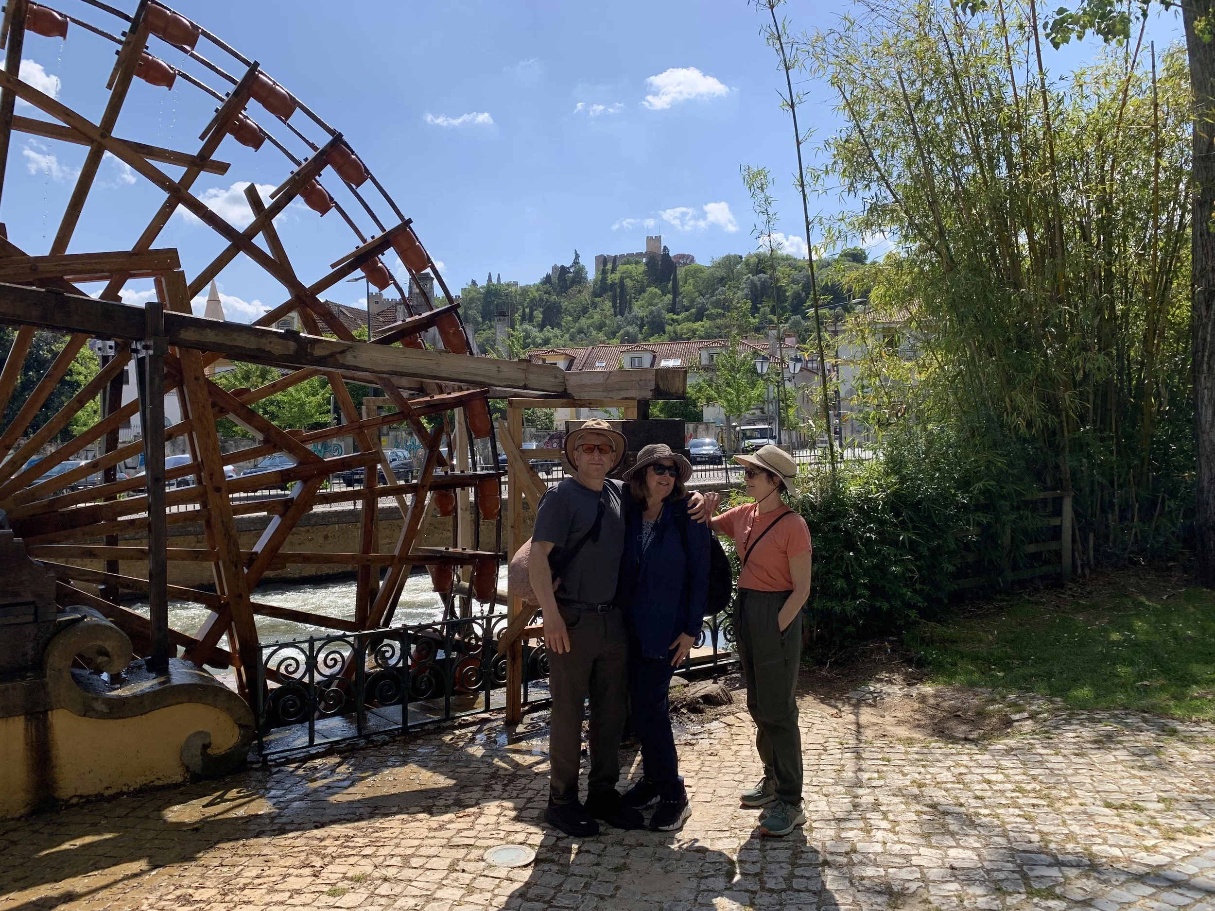 Visitors walking along the riverside in Tomar with views of the historic water wheel.