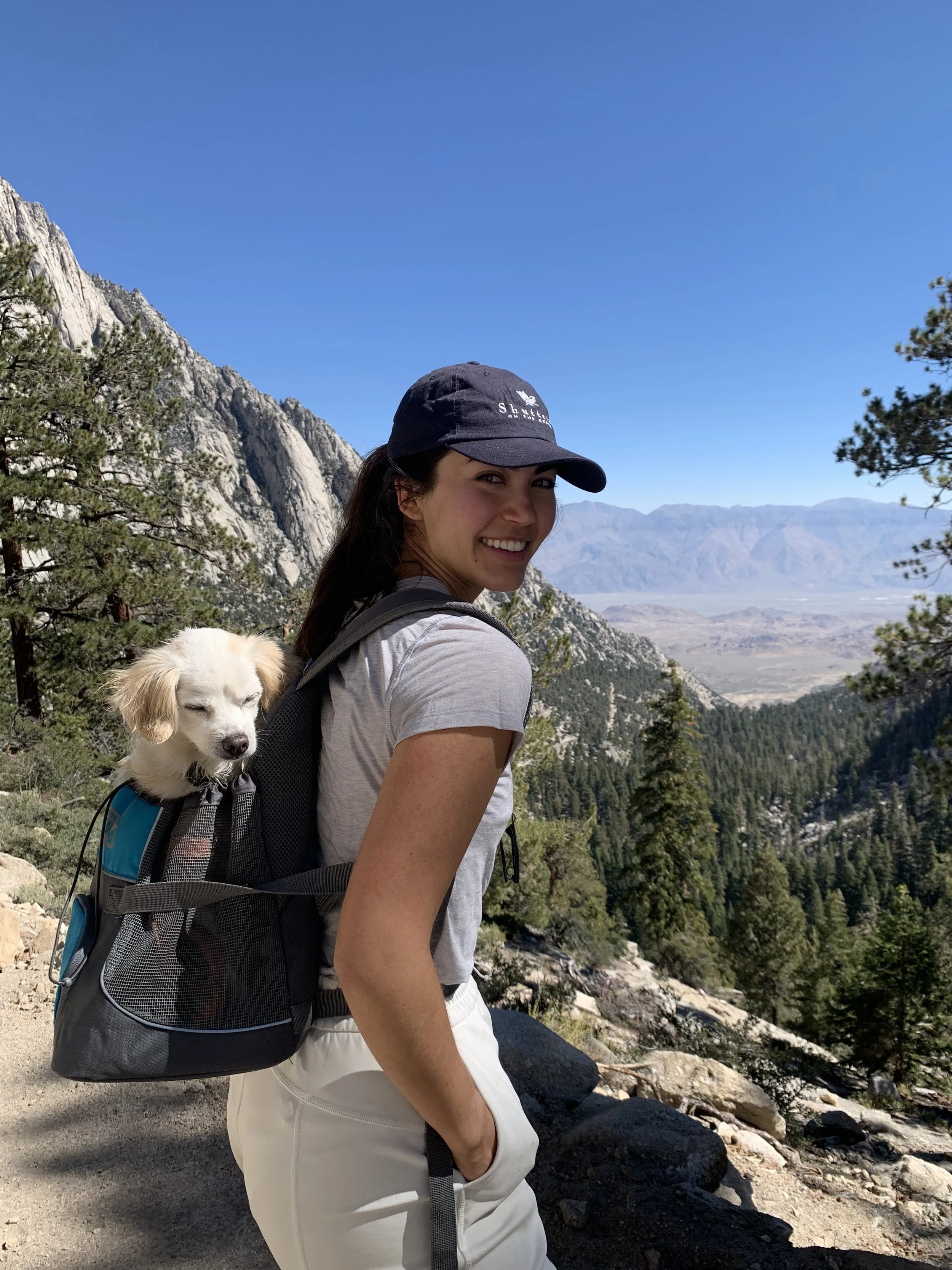 Woman hiking with a dog in the Sierra Mountains, representing a life-changing bespoke transformational travel experience with Project Latitude.