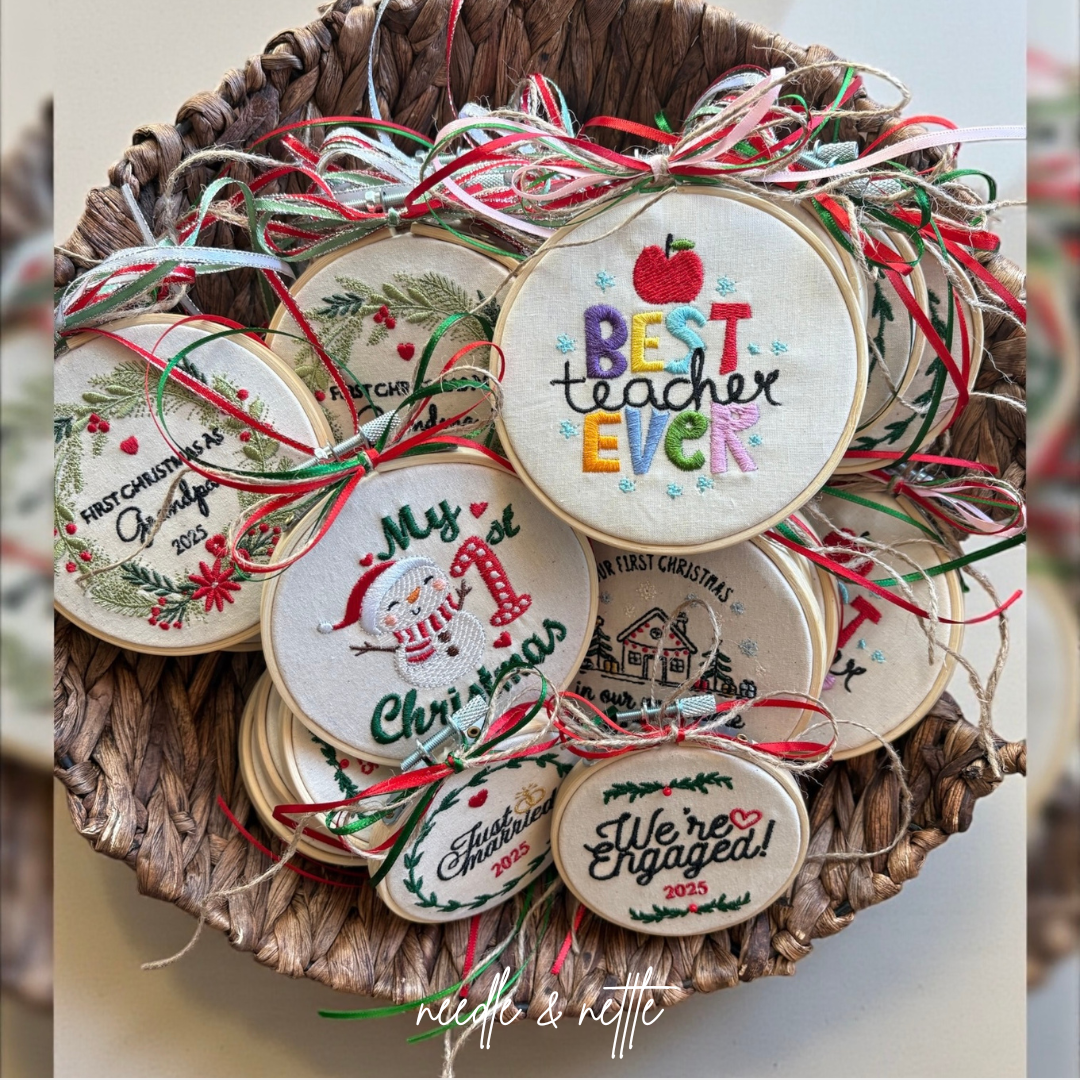 A collection of Christmas embroidery ornaments with holiday messages, including one that says 'Best teacher ever' with a red apple, hanging in a woven basket.