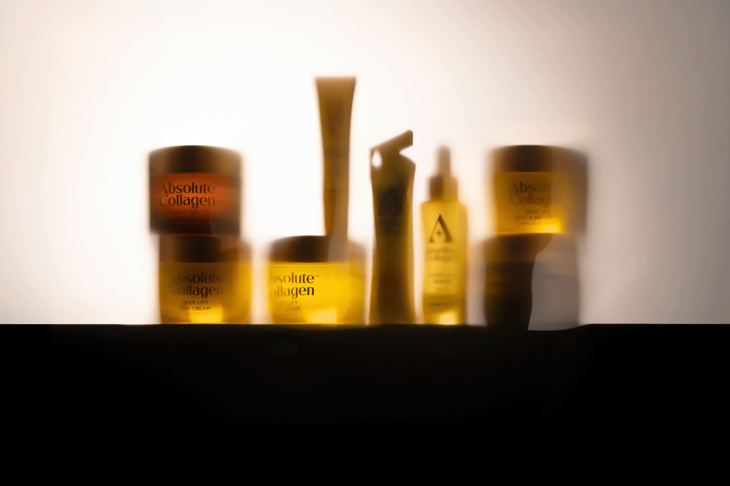 Various skincare products, including jars and bottles labeled 'Absolute Collagen,' arranged on a surface with a plain background.