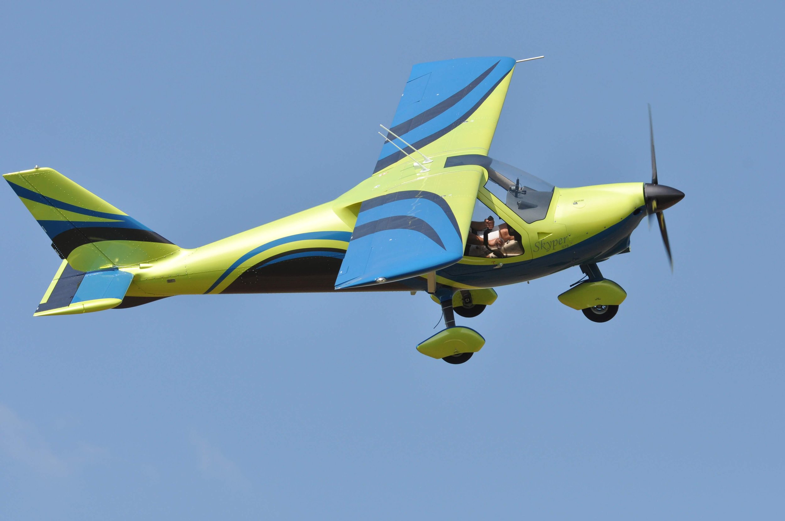 Leichtflugzeug in gelb und blau fliegt am Himmel