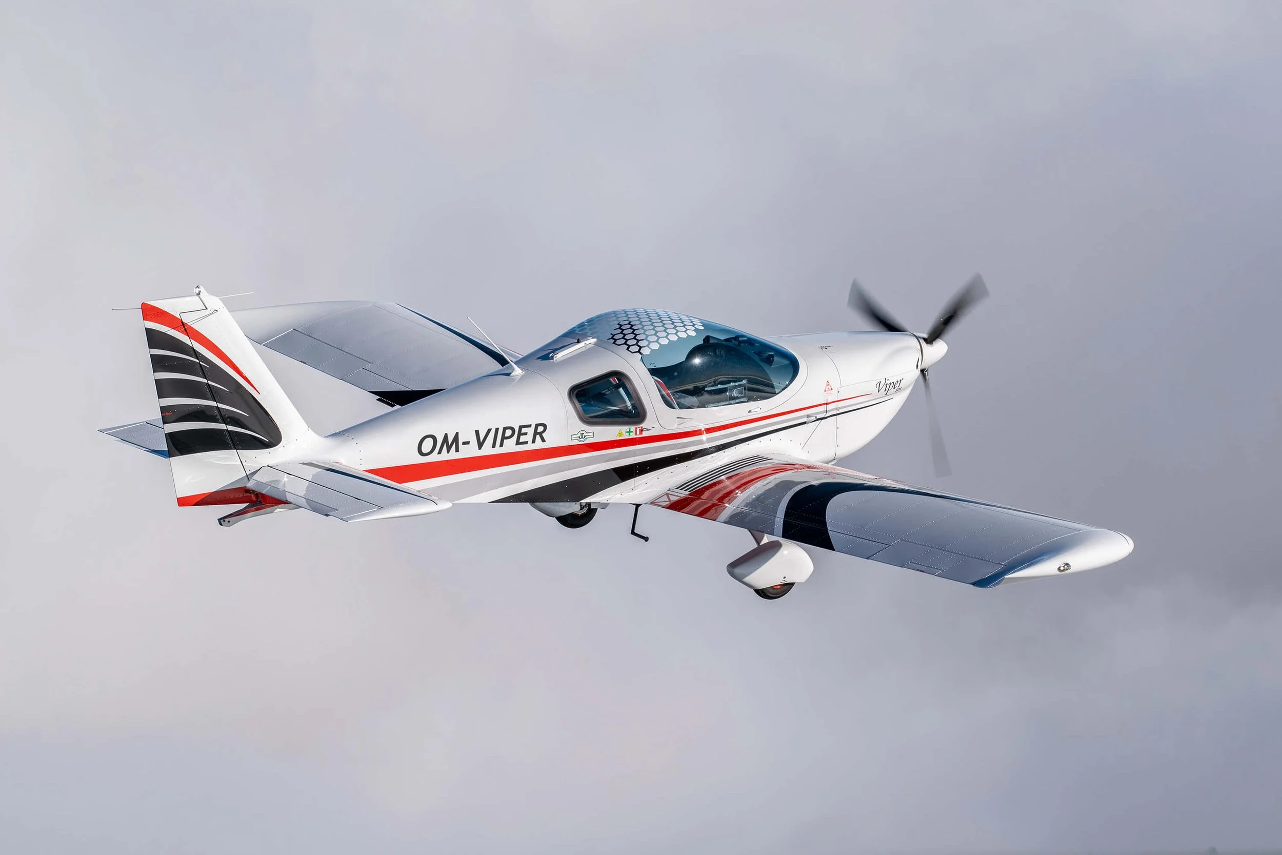 Ein weißes Flugzeug mit roten und schwarzen Linien fliegt in den Himmel.