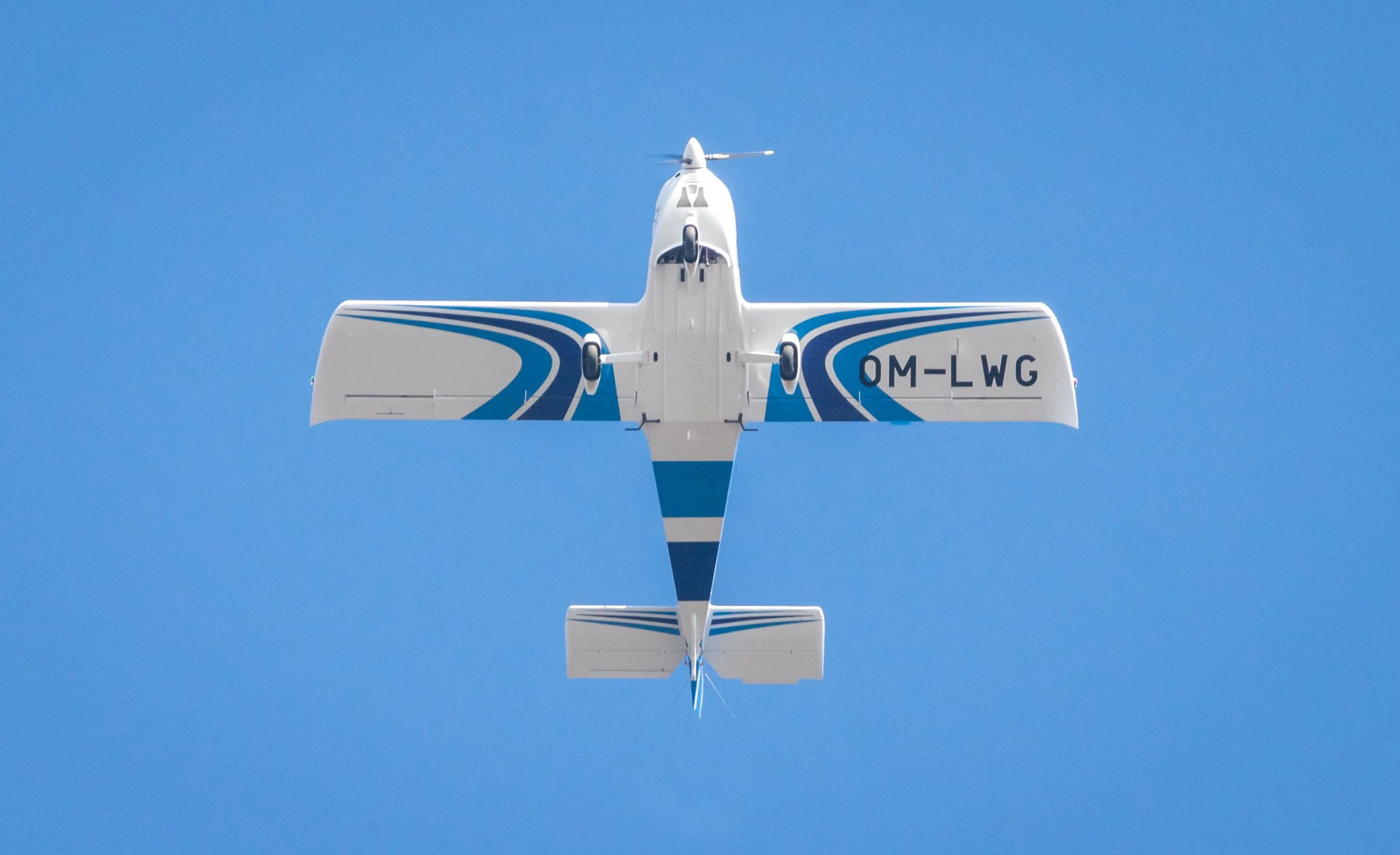 Ein Flugzeug fliegt hoch am blauen Himmel, gesehen von unten.