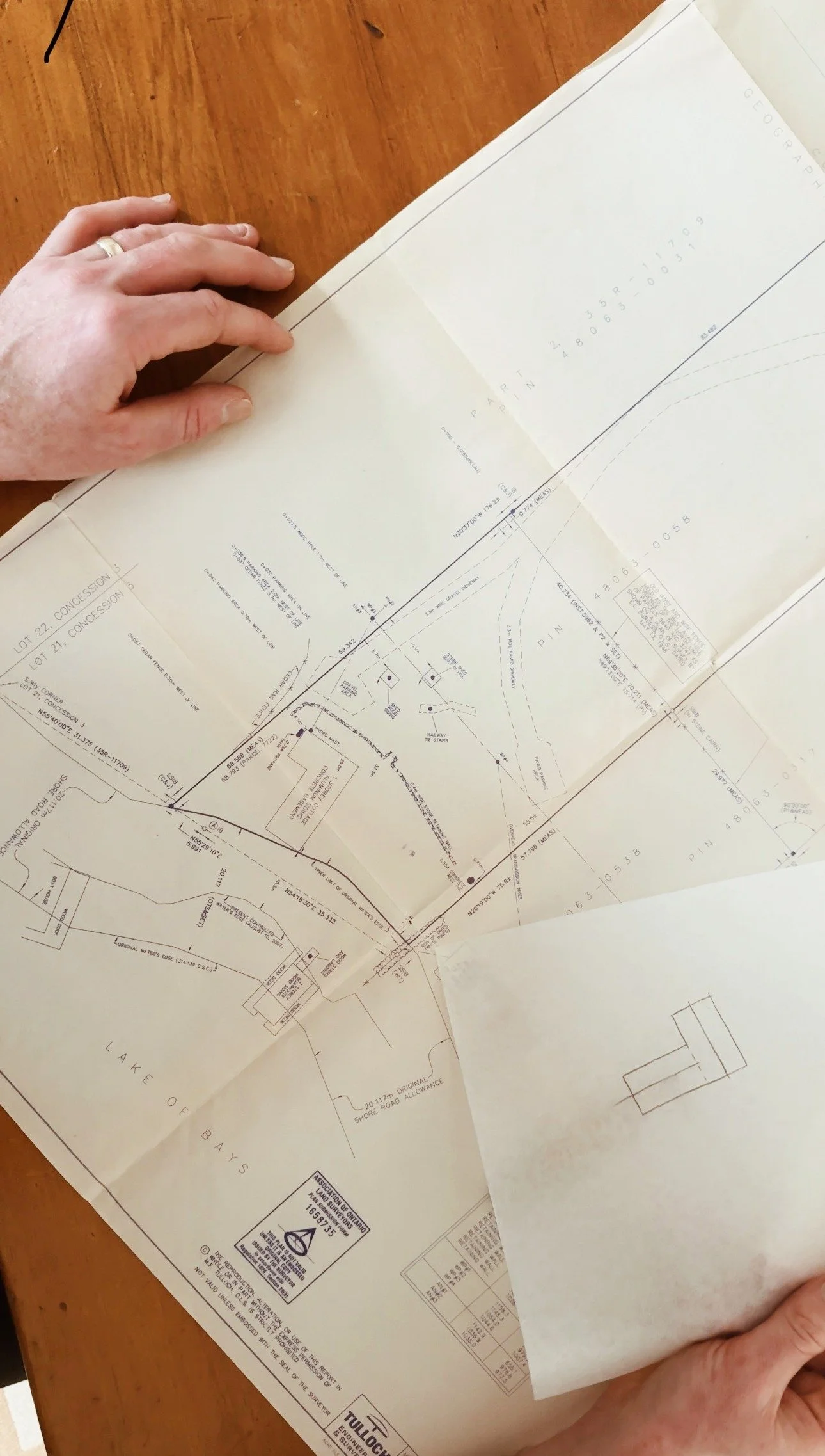 Person holding a large survey map or blueprint on a wooden table.