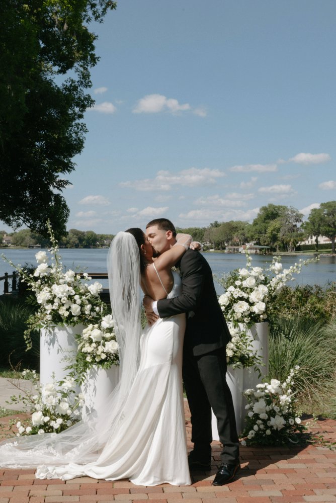 couple kissing in front of lake at lakeside wedding