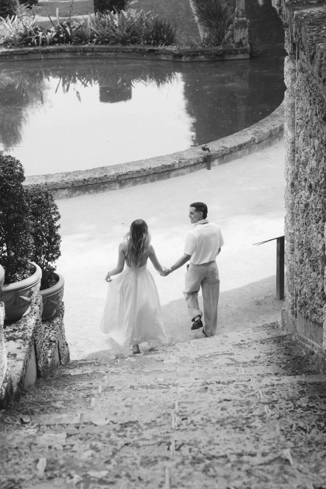 couple holding hands looking at each other on steps in vizcaya museum