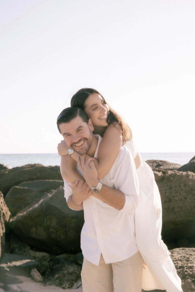 woman on fiances back during beach engagement photo session