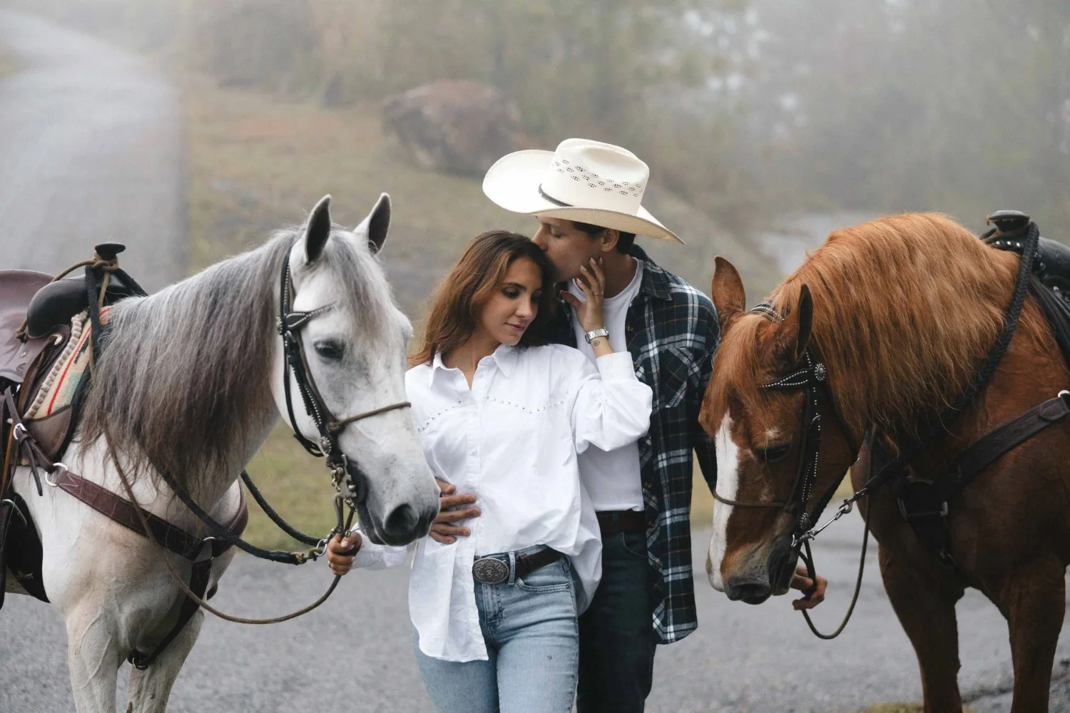 couple holding each other between horses in outdoor couples session
