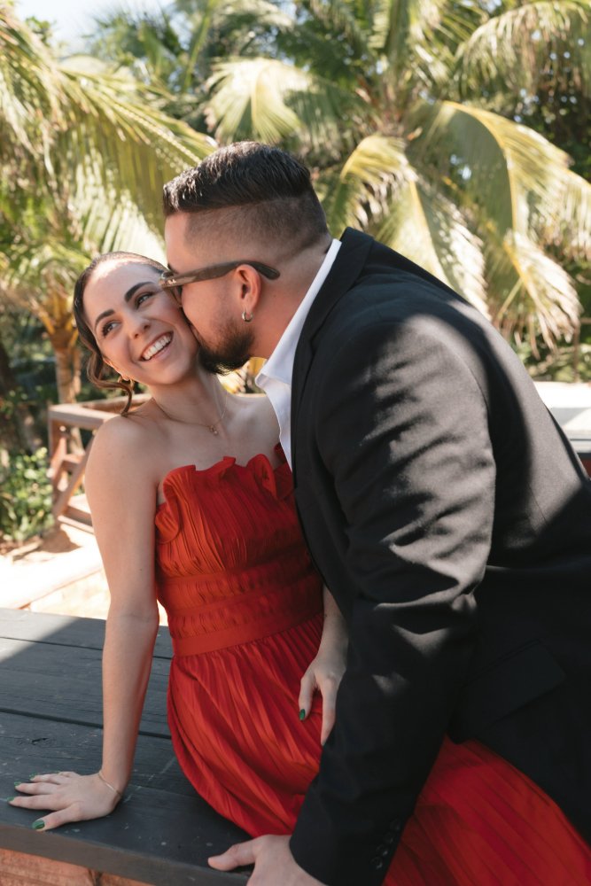 couple kissing and laughing in beach side photo session