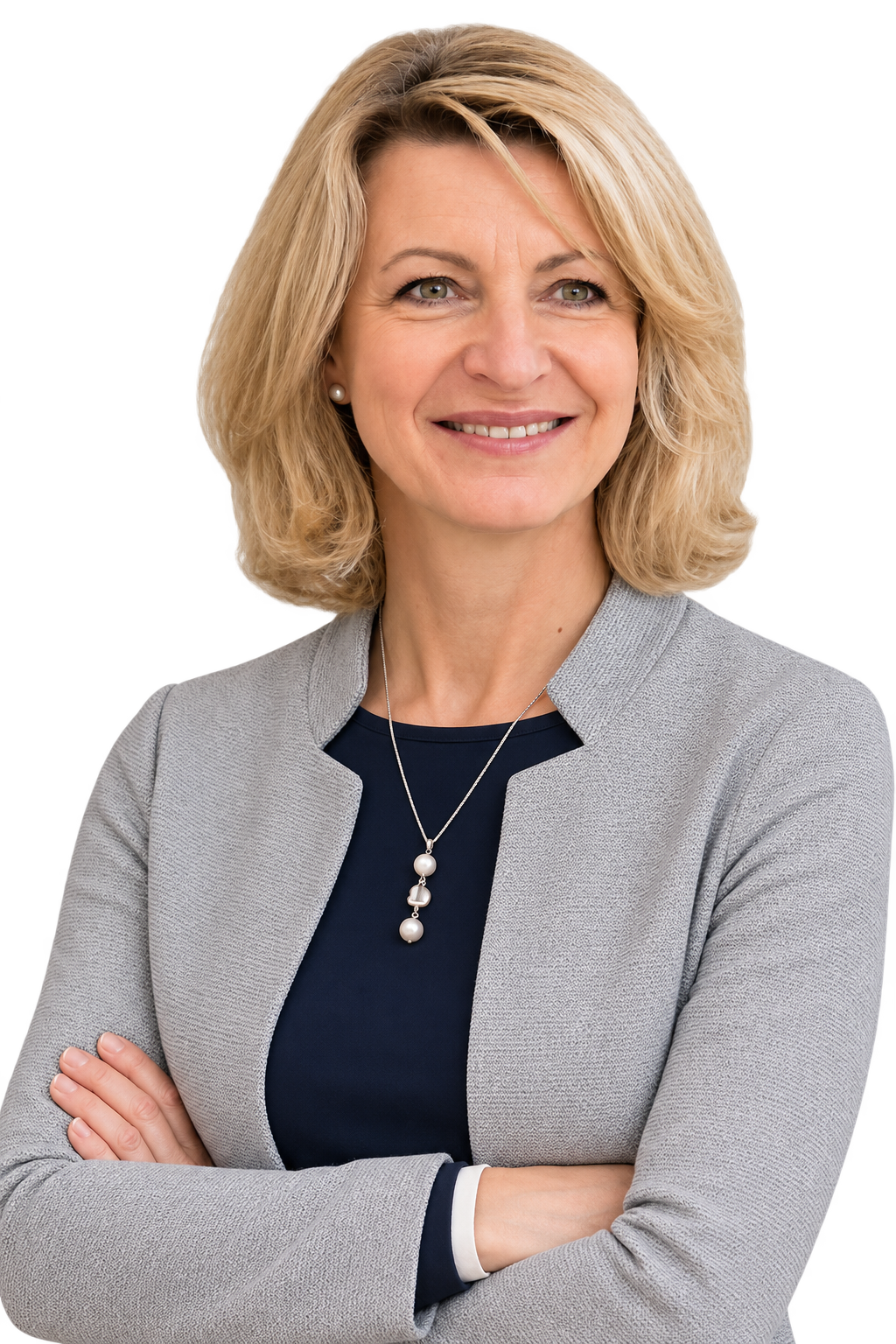 Selbstbewusste Frau mit blonden Haaren, grauem Blazer, dunklem Oberteil, Schmuck und Armkreuzierung, freundliches Lächeln.