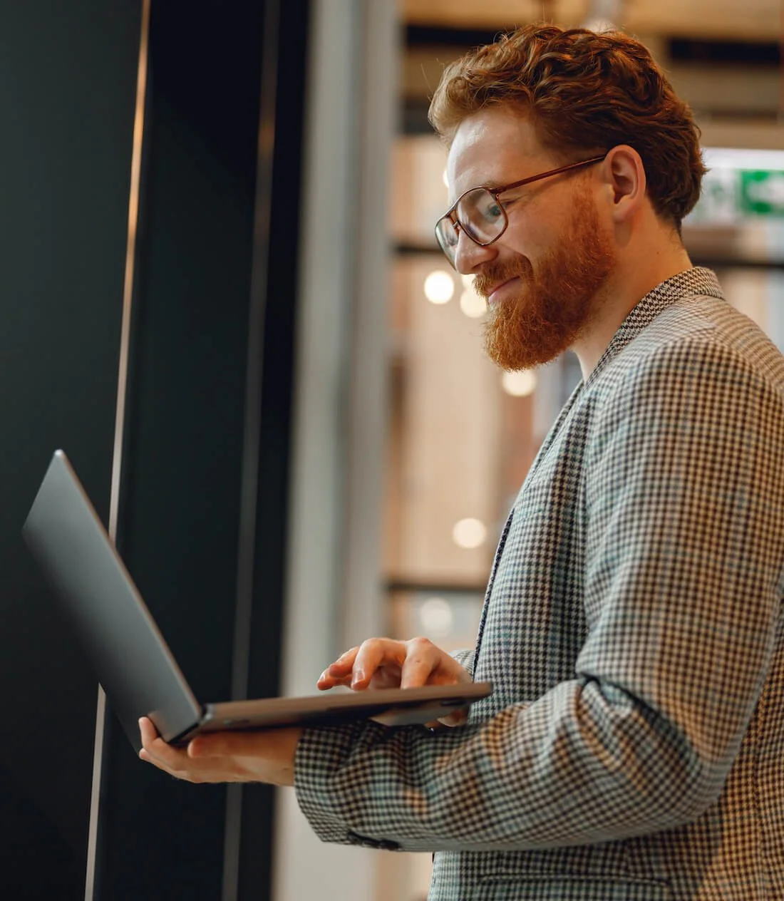 professional man standing holding a laptop and smiling