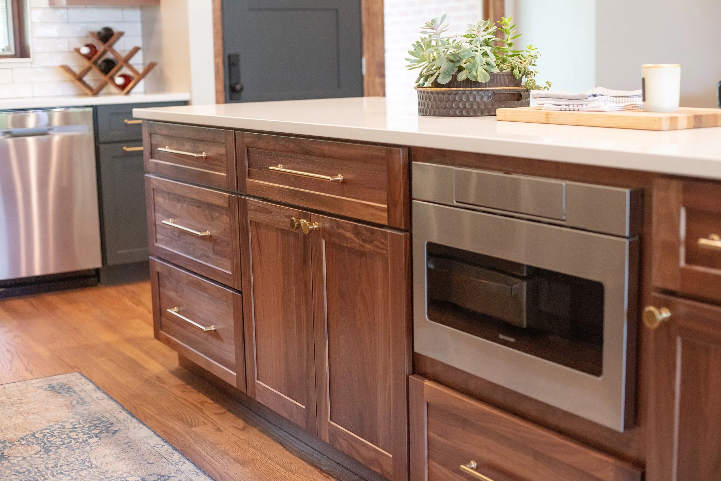 Kitchen with wooden cabinets, stainless steel oven, and decorative plants on the countertop.