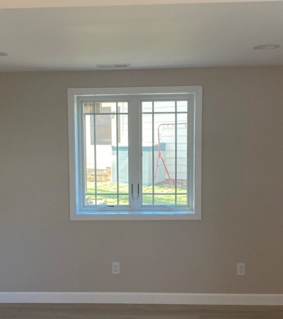 Empty room with a window showing an outdoor yard area, a grass lawn, a hot tub, and a playground frame.