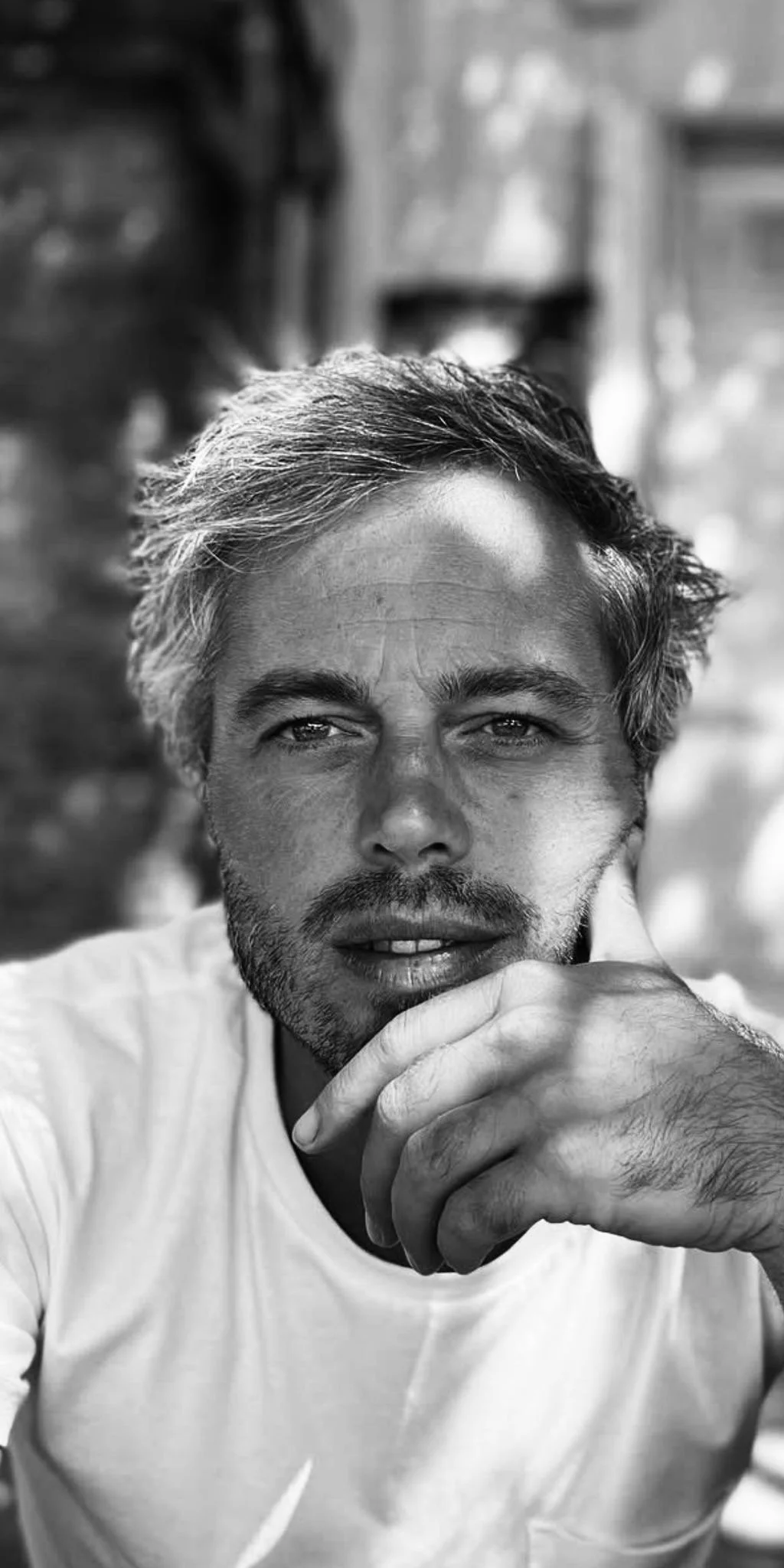 A man with curly hair and facial hair playing a saxophone.