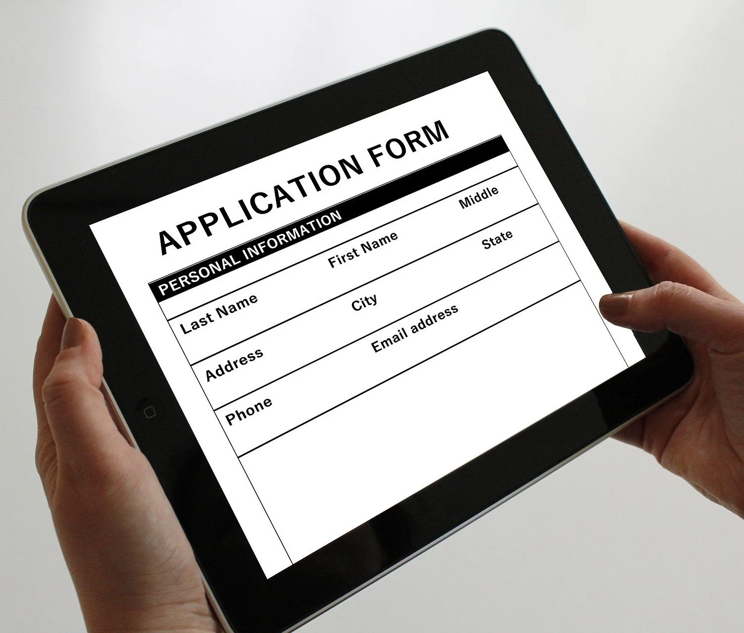 A person holding a tablet displaying a blank application form with sections for personal information, including name, address, phone, email, and other details.
