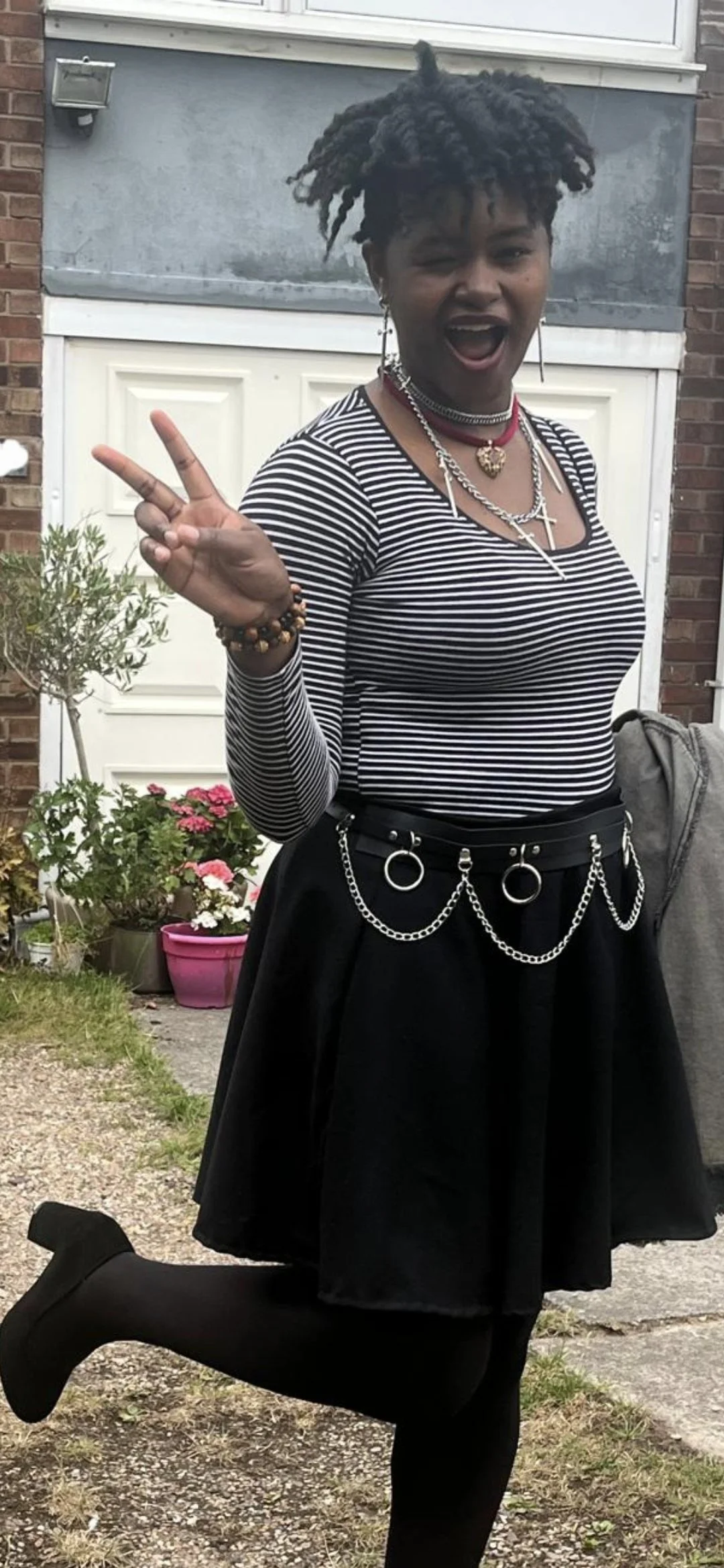 a girl wearing a black and white striped tshirt, a black and silver belt, and a plain black a line miniskirt