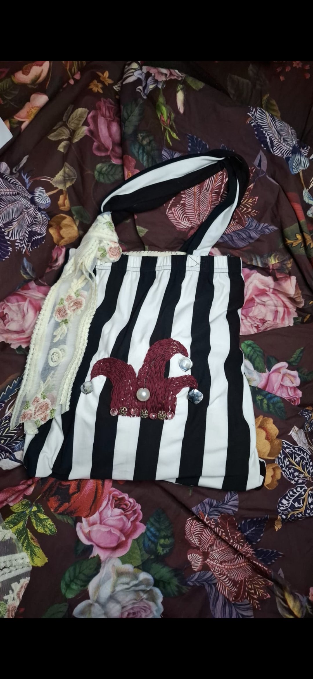 a black and white striped tote bag with embroidered jester hat design