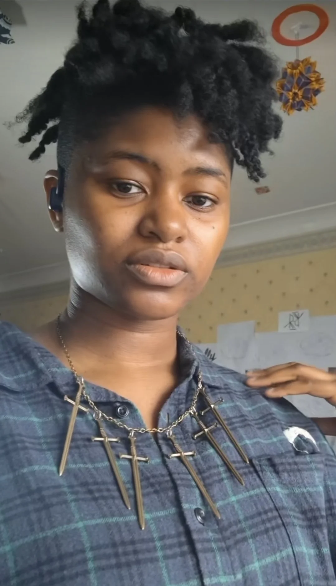 a girl with black hair wearing a bronze dagger necklace