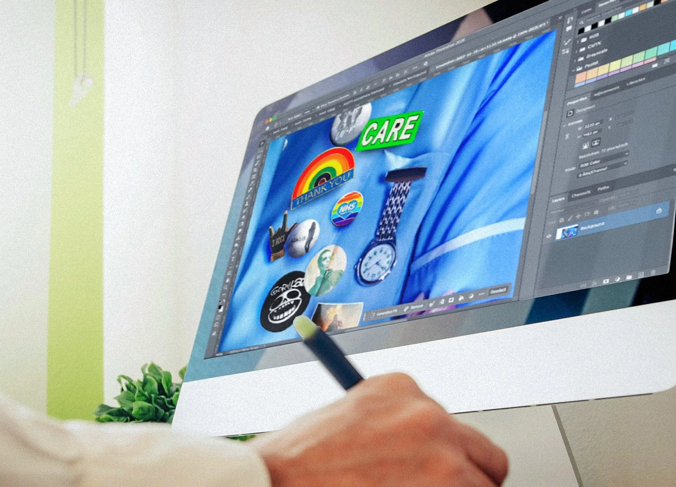 Computer screen displaying graphics and stickers on blue background, with a person's hand using a stylus in the foreground.