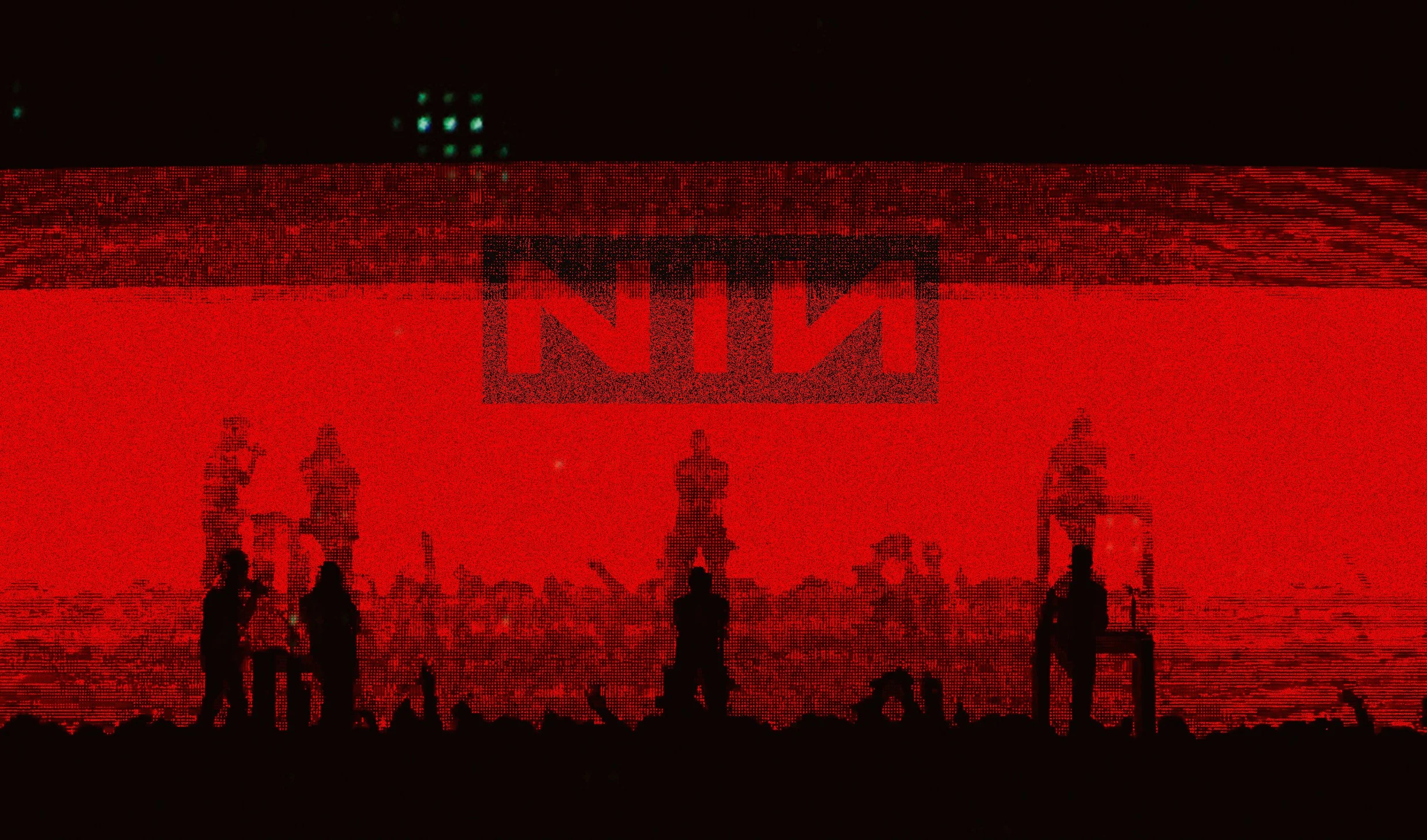 Silhouettes of people standing on a stage with a large red screen displaying the Netflix logo and pixelated figures.