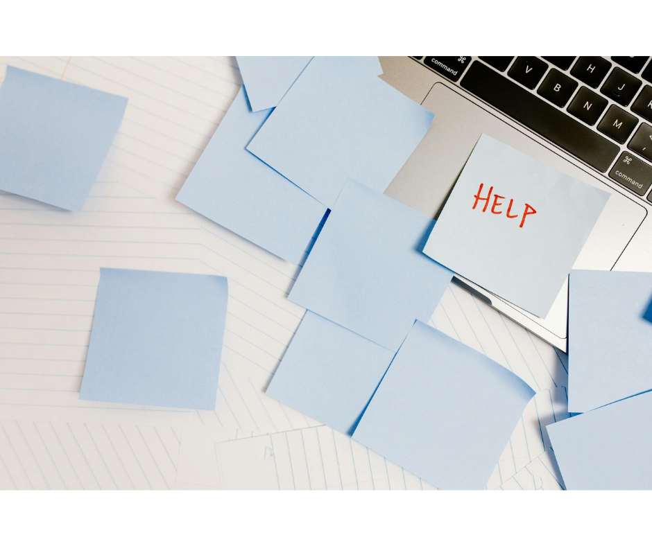 Sticky notes on a desk next to a laptop, one reading HELP