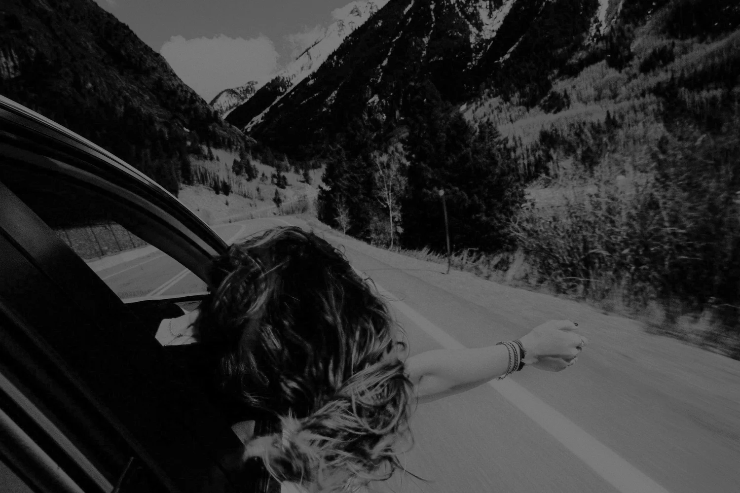 Woman looking out a car window on a mountain road