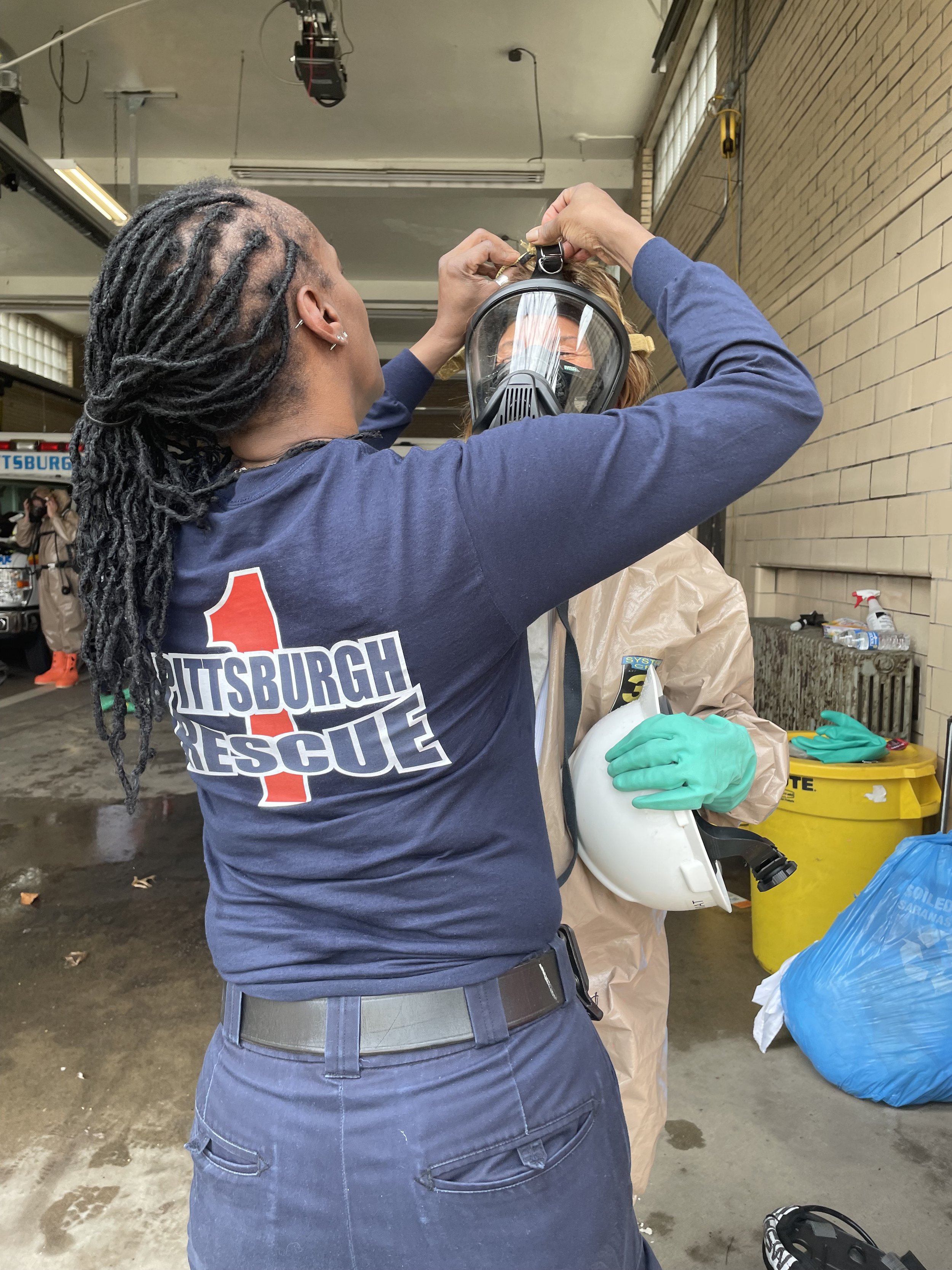 Paramedic Raina Lewis helps a fellow medic dress out for a Hazmat training
