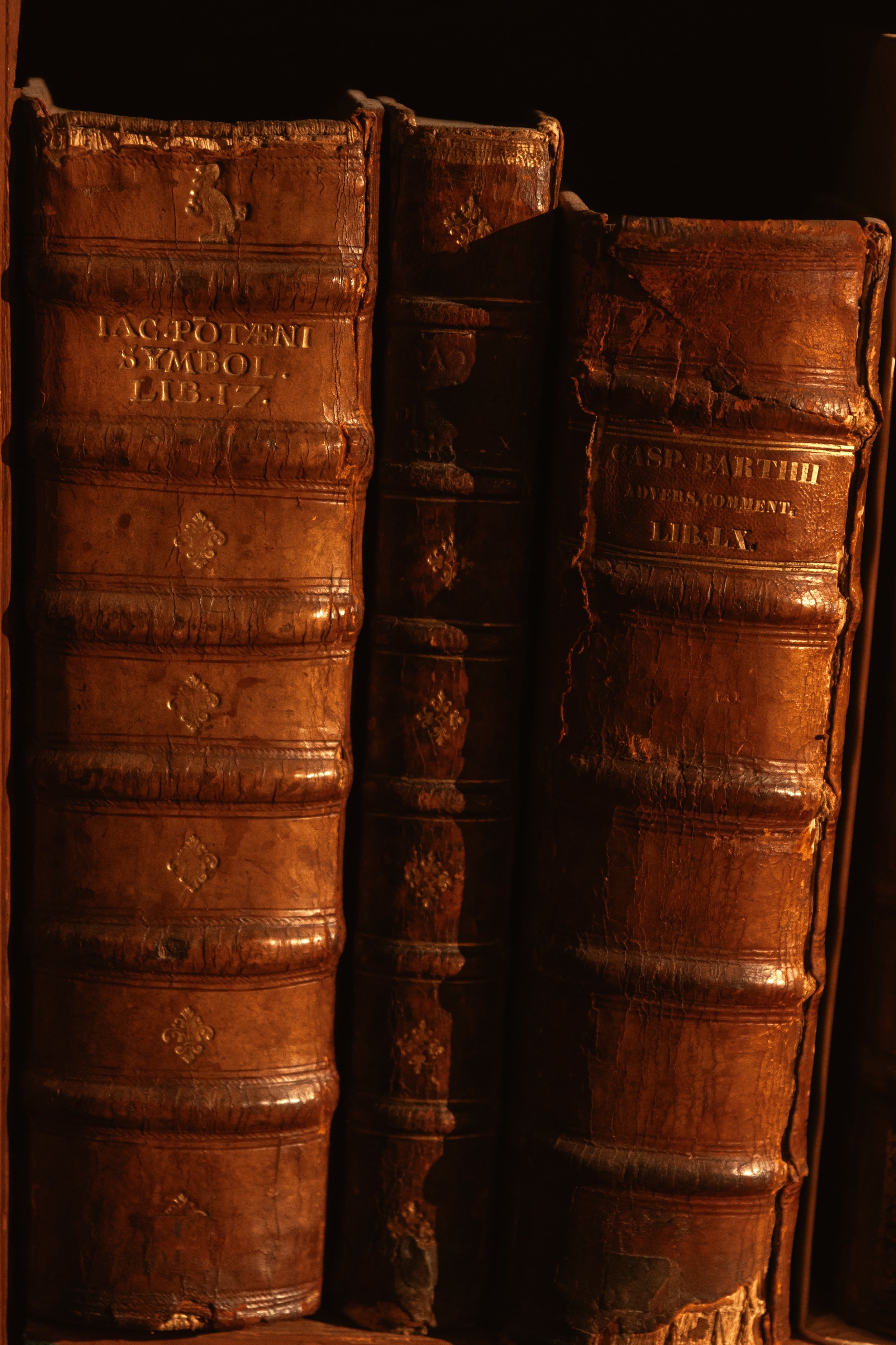 Antieke, versleten leren boeken op een plank.