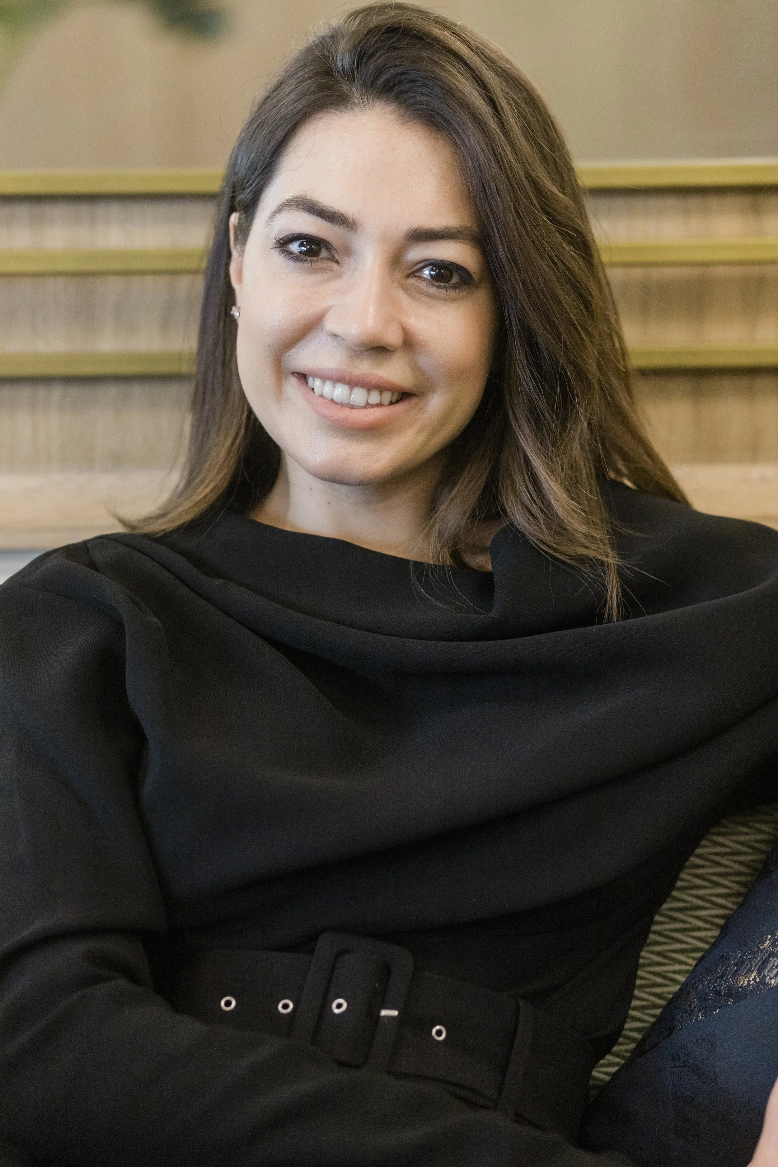 Smiling woman in black top sitting indoors.