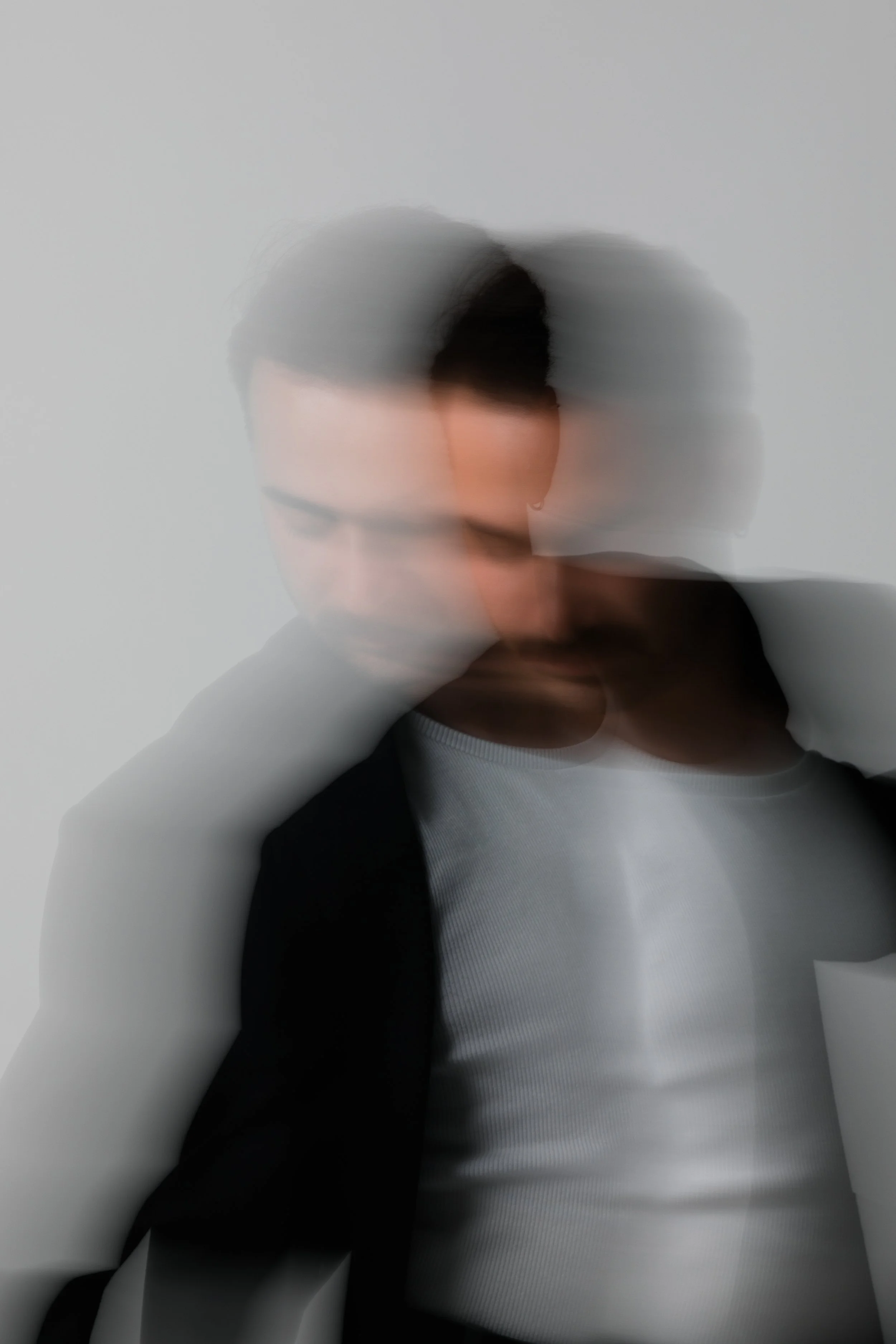 Blurred portrait of a person wearing a jacket and white shirt, captured in motion.