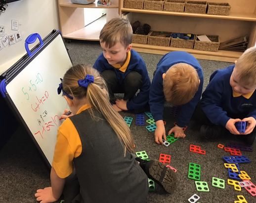 Elementary school children learning addition with colorful math manipulatives and a whiteboard