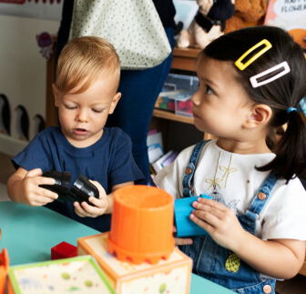 Young boy and girl playing with colorful toy blocks and a small orange toy drum indoors