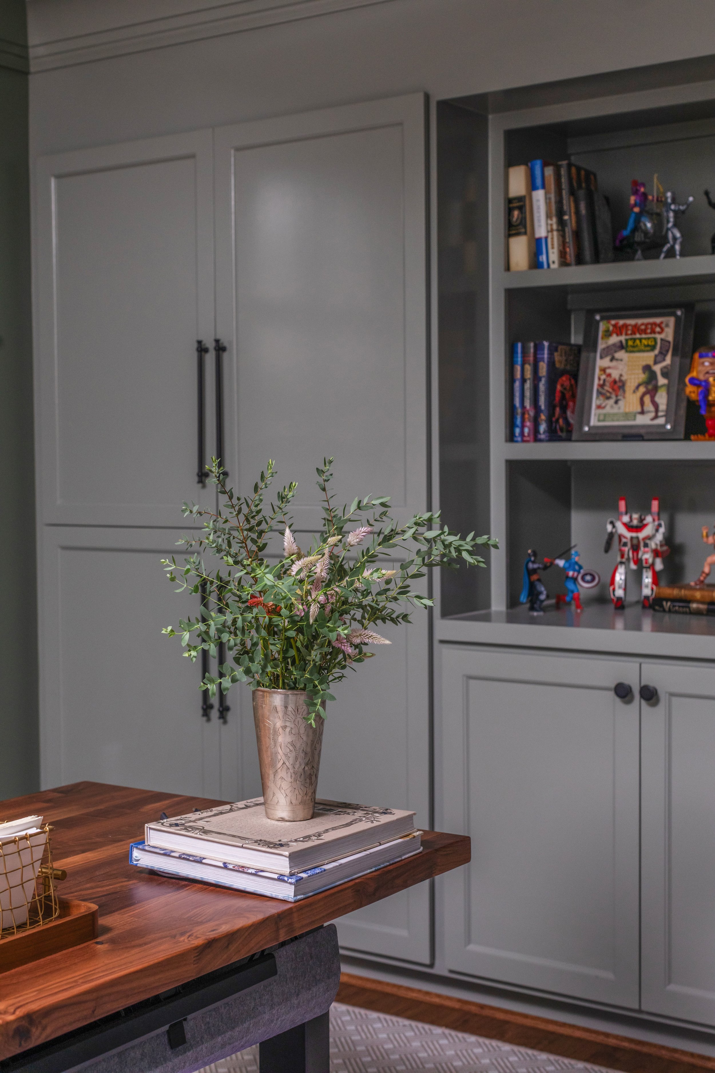 Custom basement office cabinetry designed to display comics and superhero collectibles