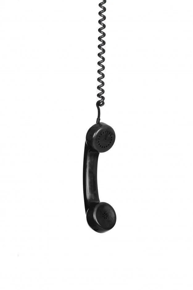 Black corded telephone handset hanging from a curly cord against a white background.