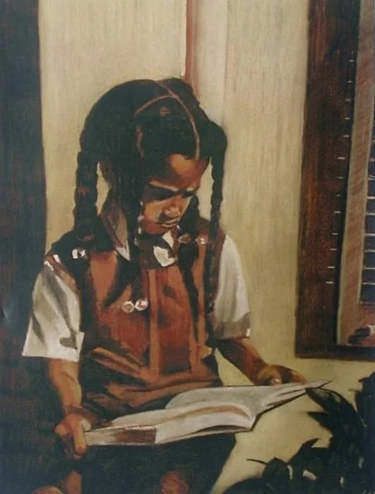 A young girl with braided hair and glasses reading a book while sitting at a desk.