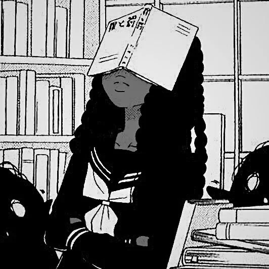 A person with long, curly hair has a cardboard box on their head and is sitting at a desk in a library or bookstore surrounded by books.