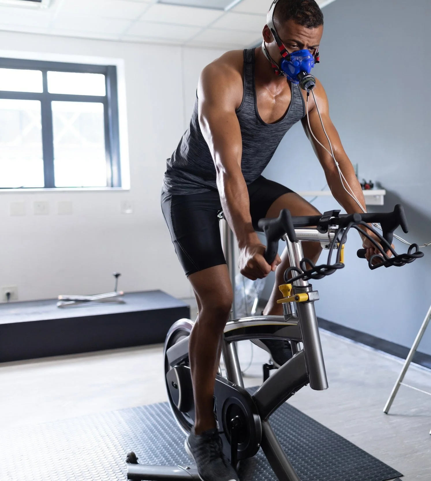 A man undergoing a VO2max test on a stationary bike in a the Healthstar Club, a lab-like environment with medical equipment and a computer