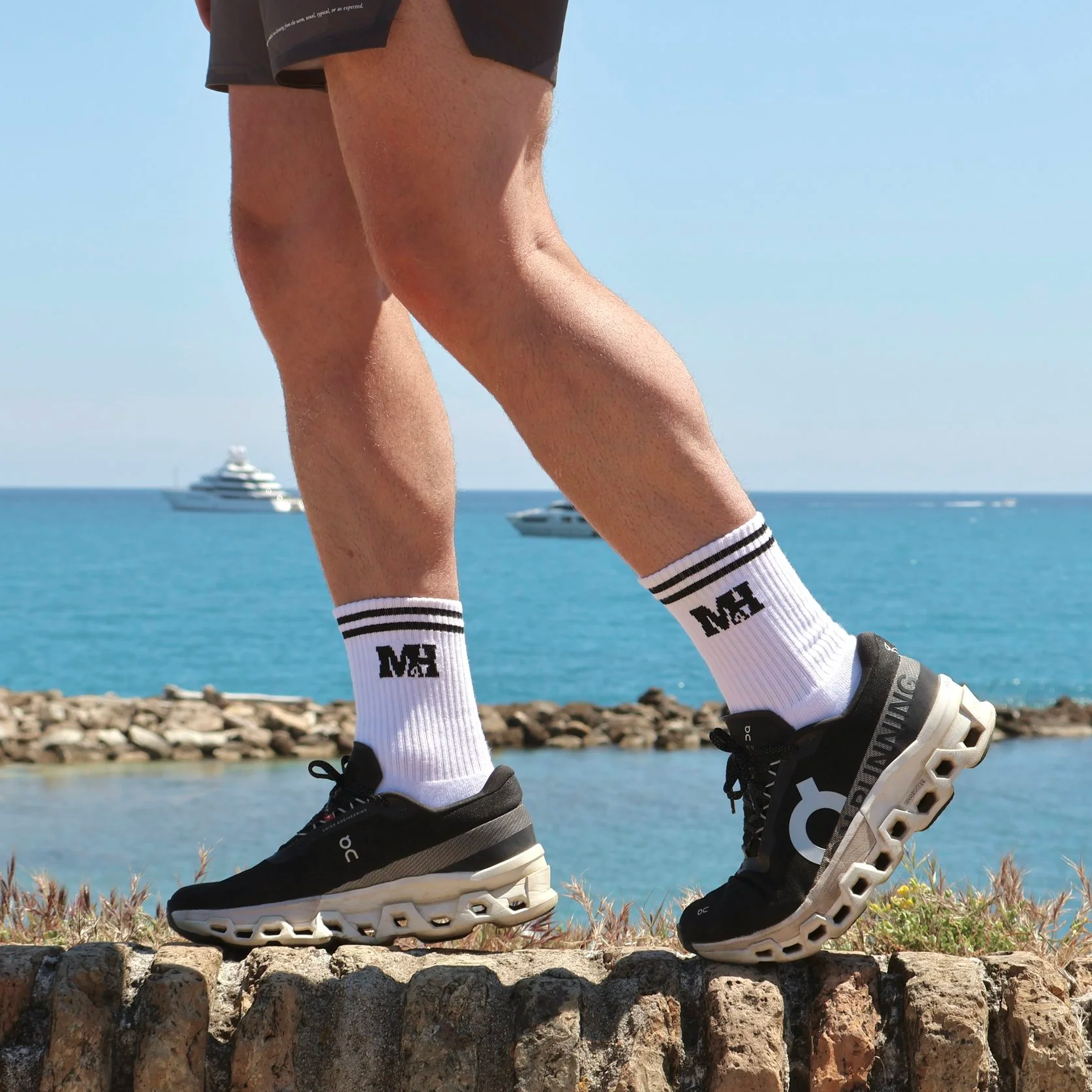 person with m4 socks on a wall in france with superyachts in the background