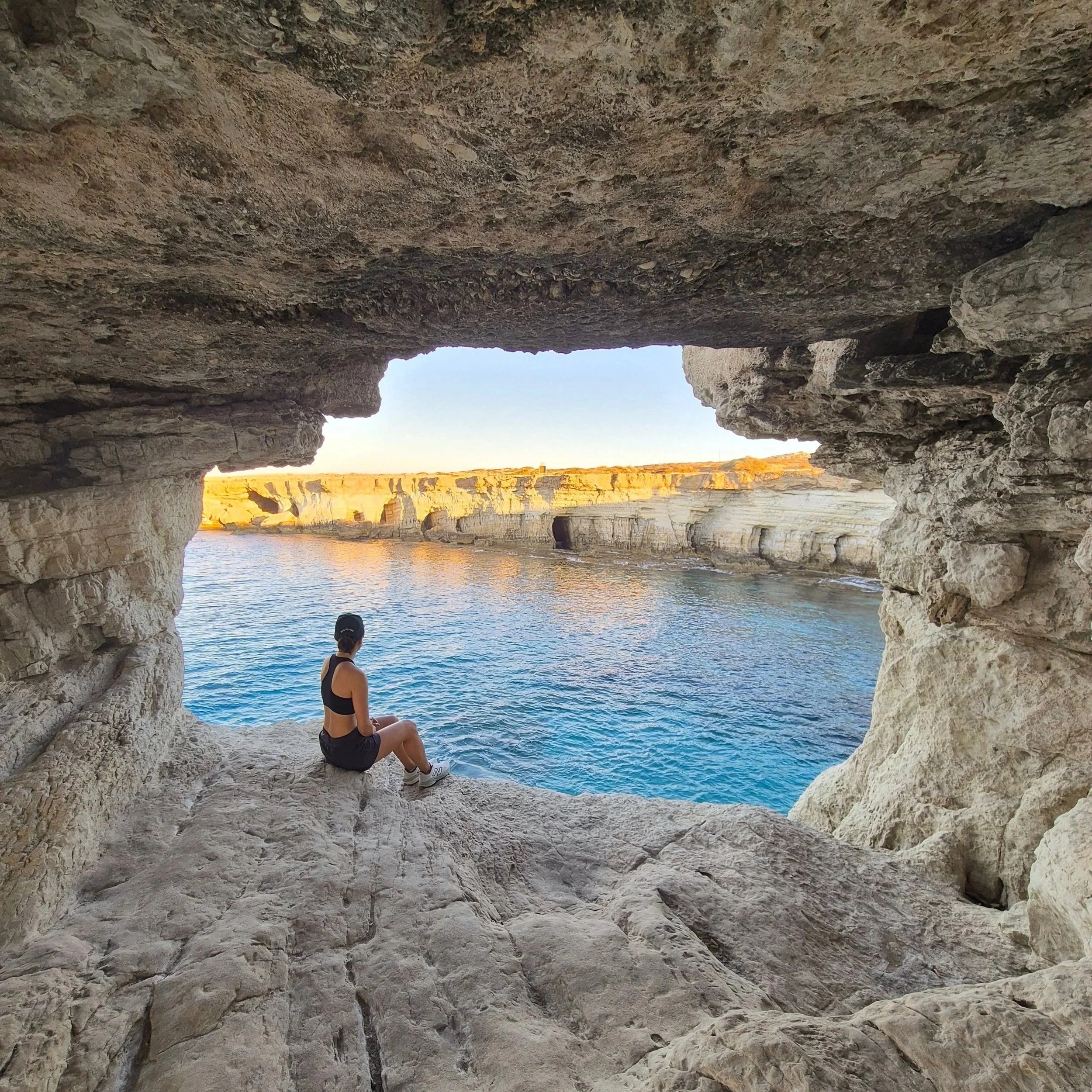 woman in a cave looking out to see on a hike in cyprus
