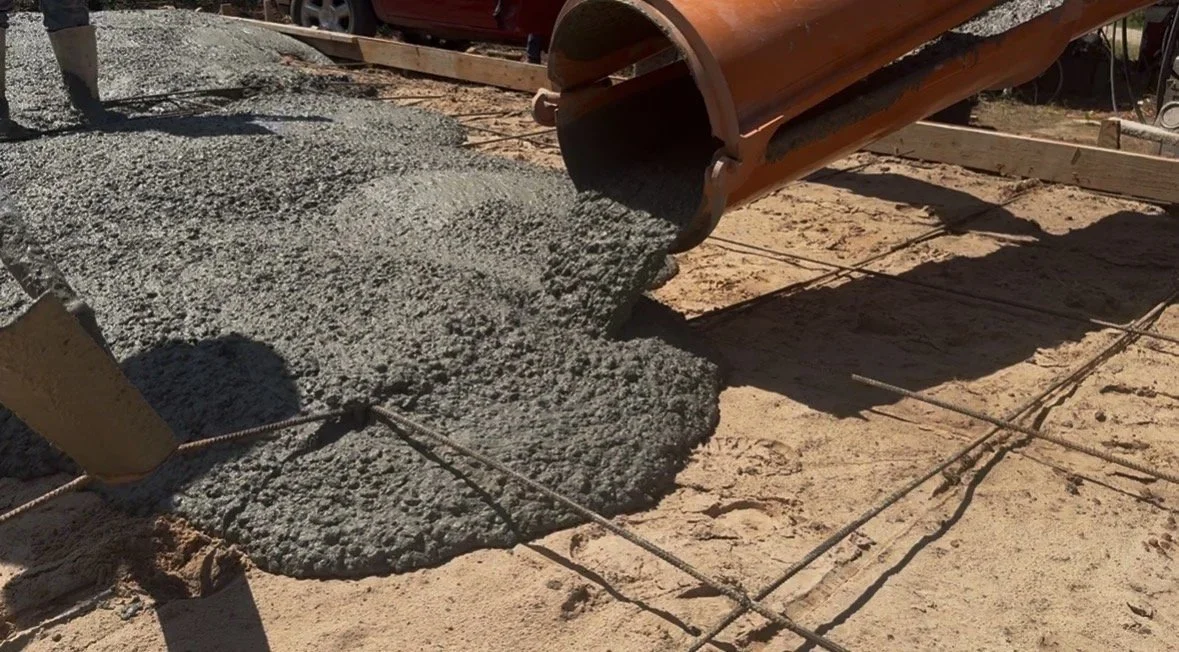 Concrete being poured onto a construction site with rebar grid for reinforcement.