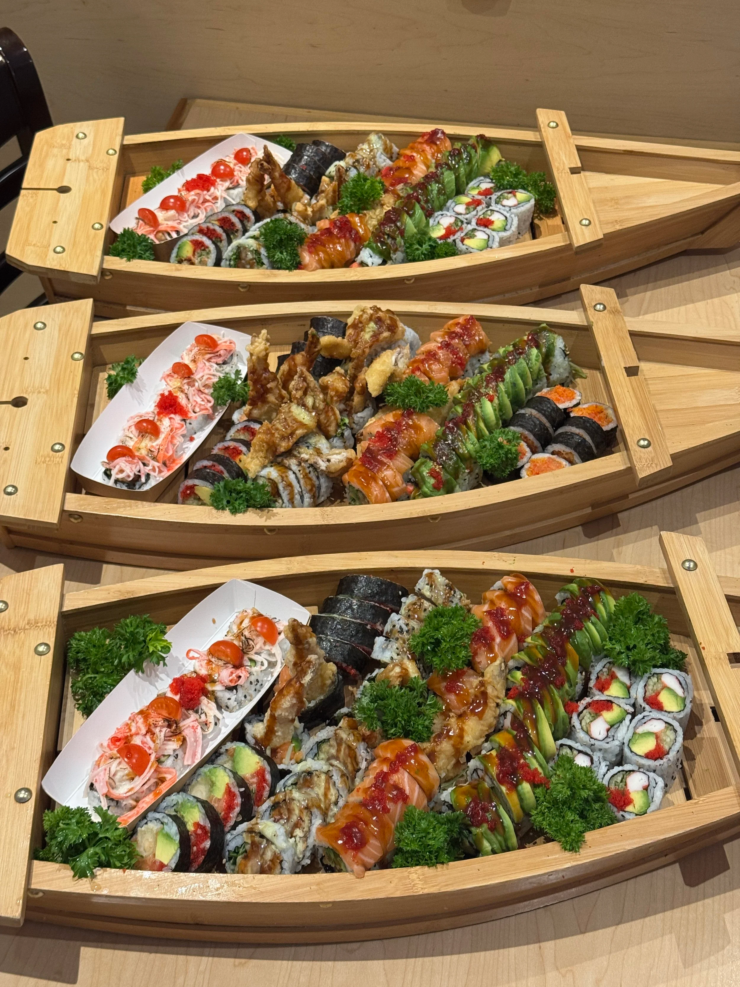 Three sushi boats with assorted sushi rolls. Catering event.