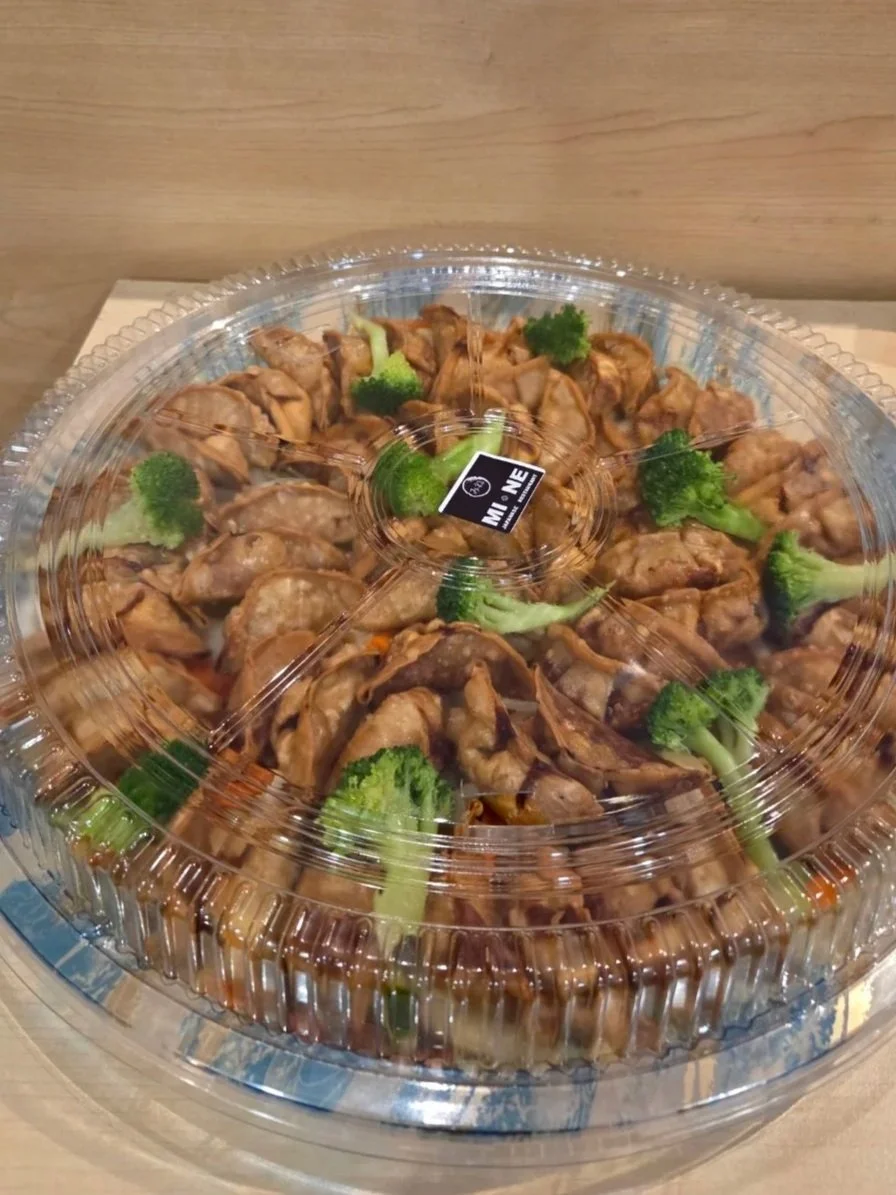 A round plastic container with a clear lid, filled with cooked chicken pieces and broccoli florets.