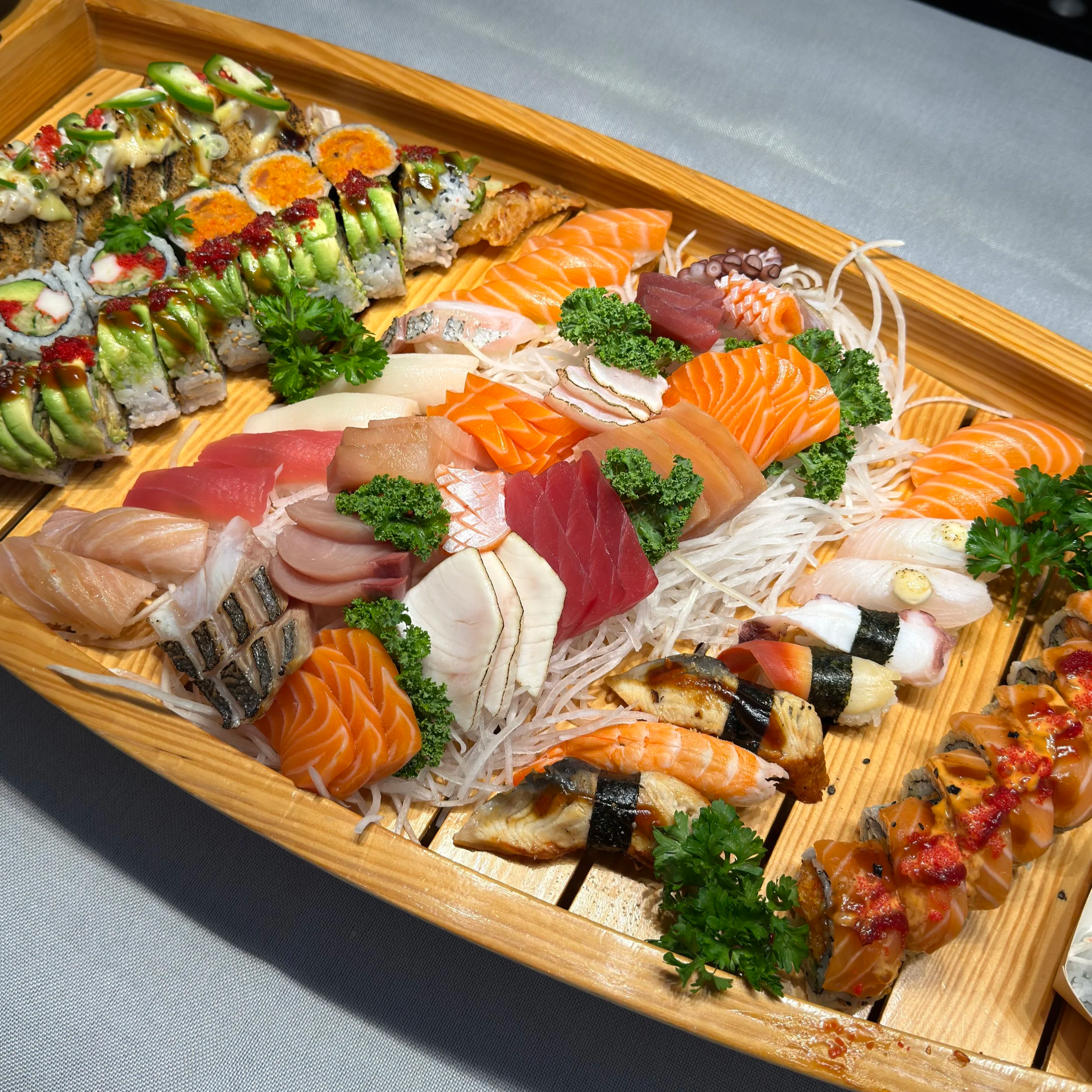 Assorted sashimi and sushi rolls on a wooden platter. Sushi boat, catering, takeout.