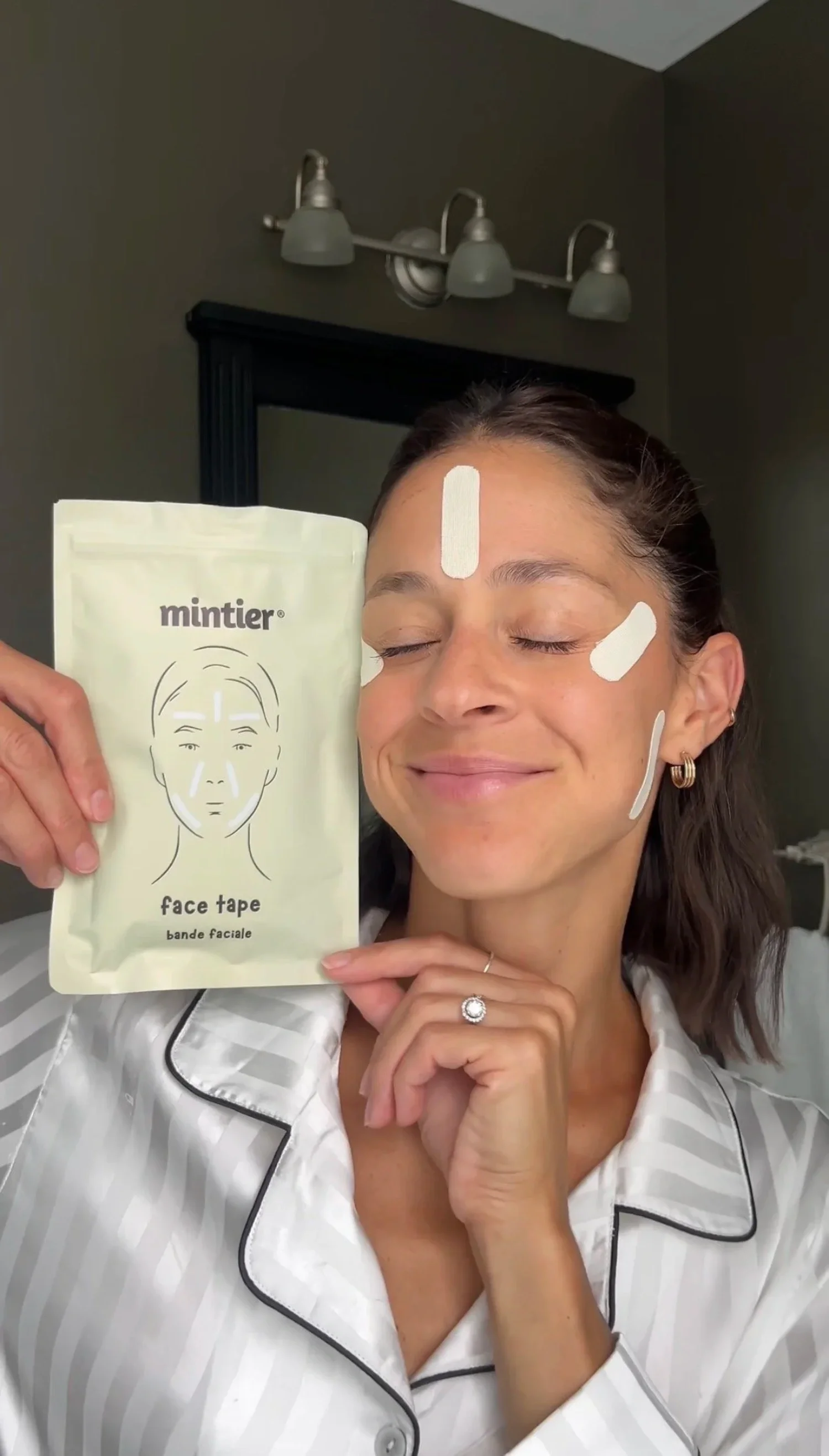 Kate Shewaga with face tape on her face, holding a package labeled 'mintier face tape'.