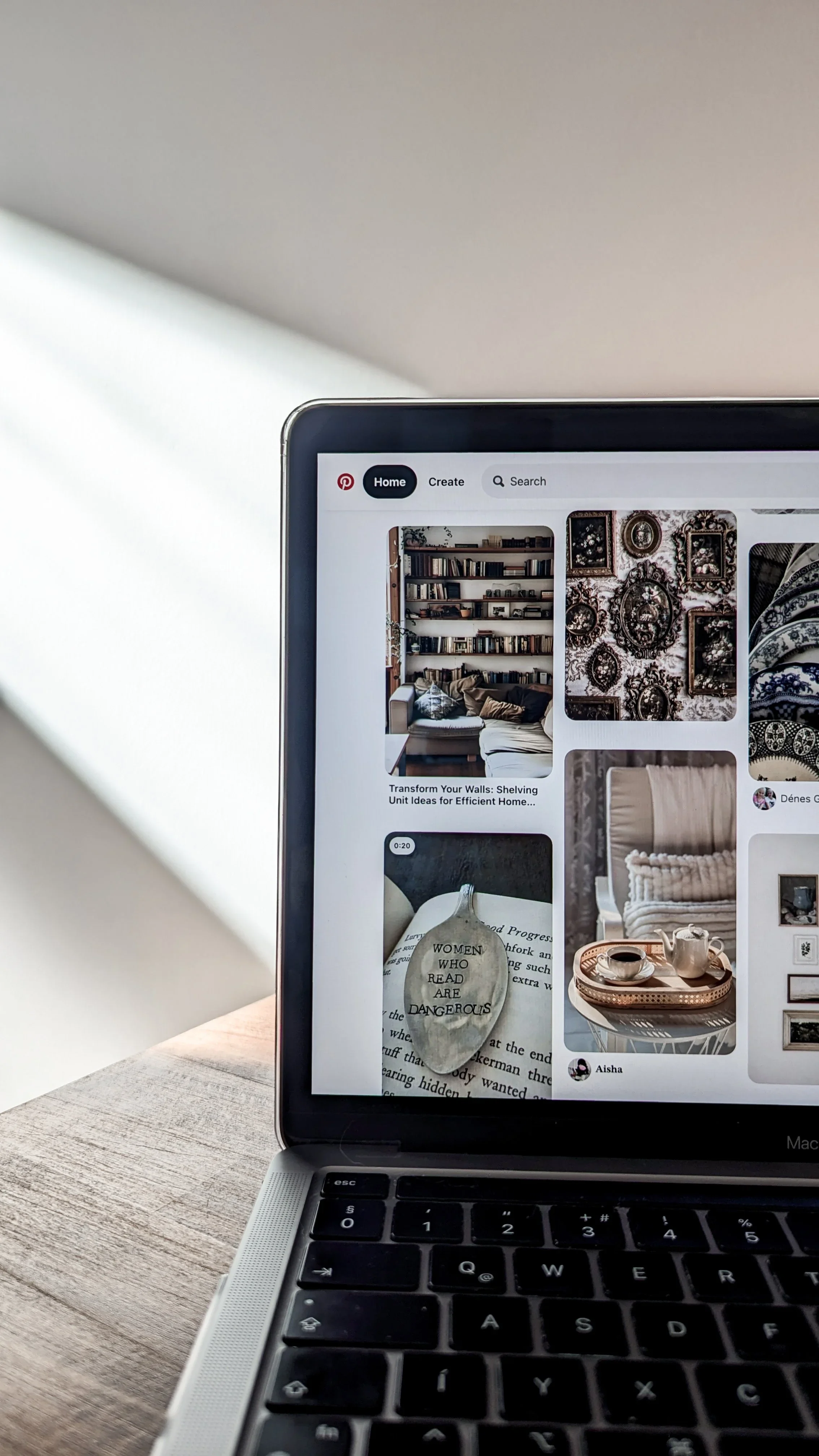 A laptop screen displaying Pinterest with images of interior decor and books.