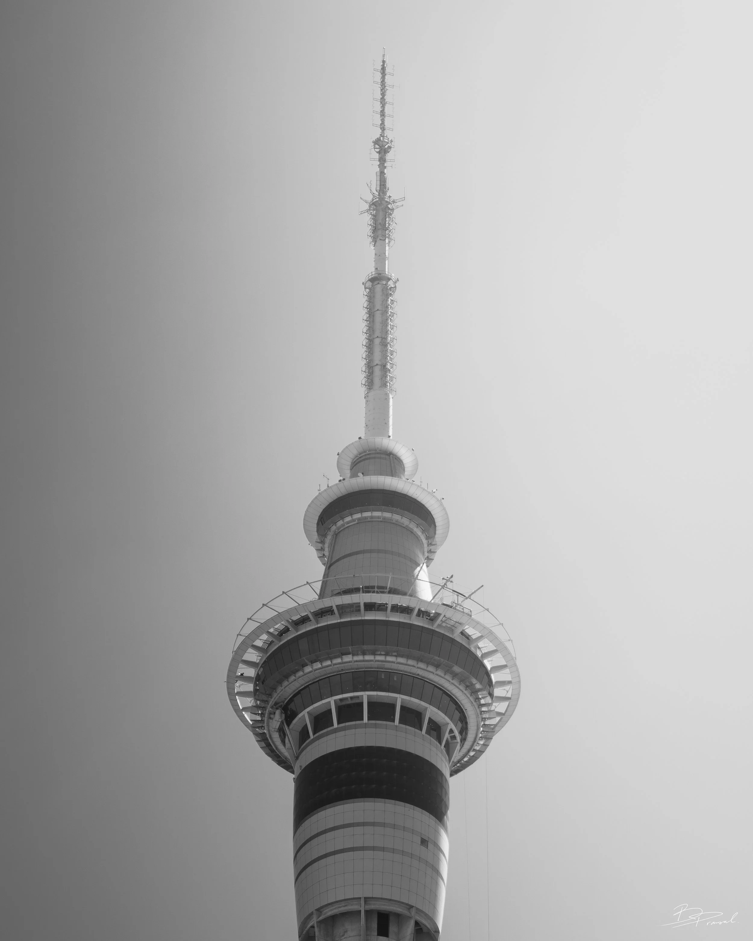 Black and white photo of a tall telecommunications tower with multiple antennas extending from a rounded base