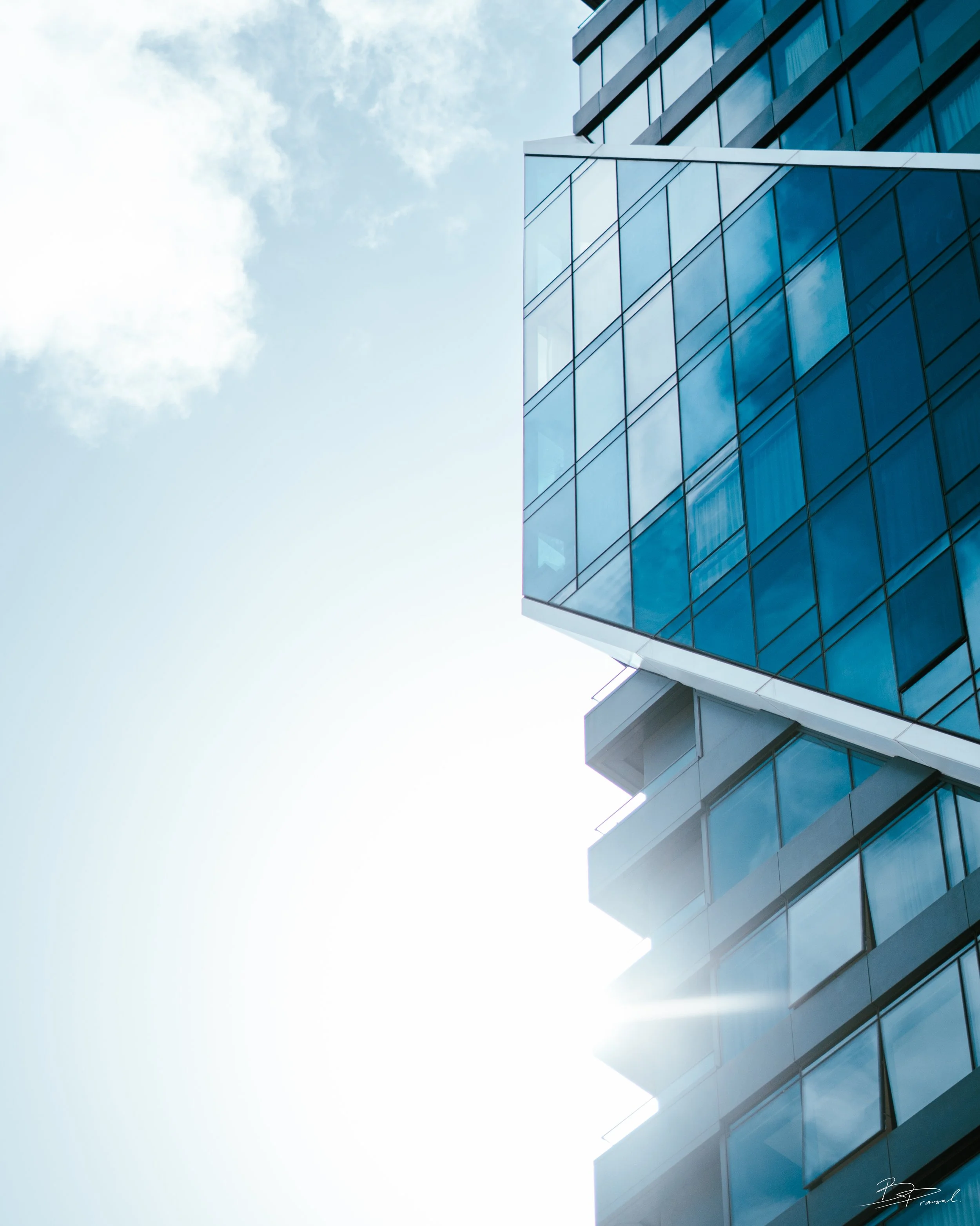 Modern glass office building reflecting the sky on a sunny day.