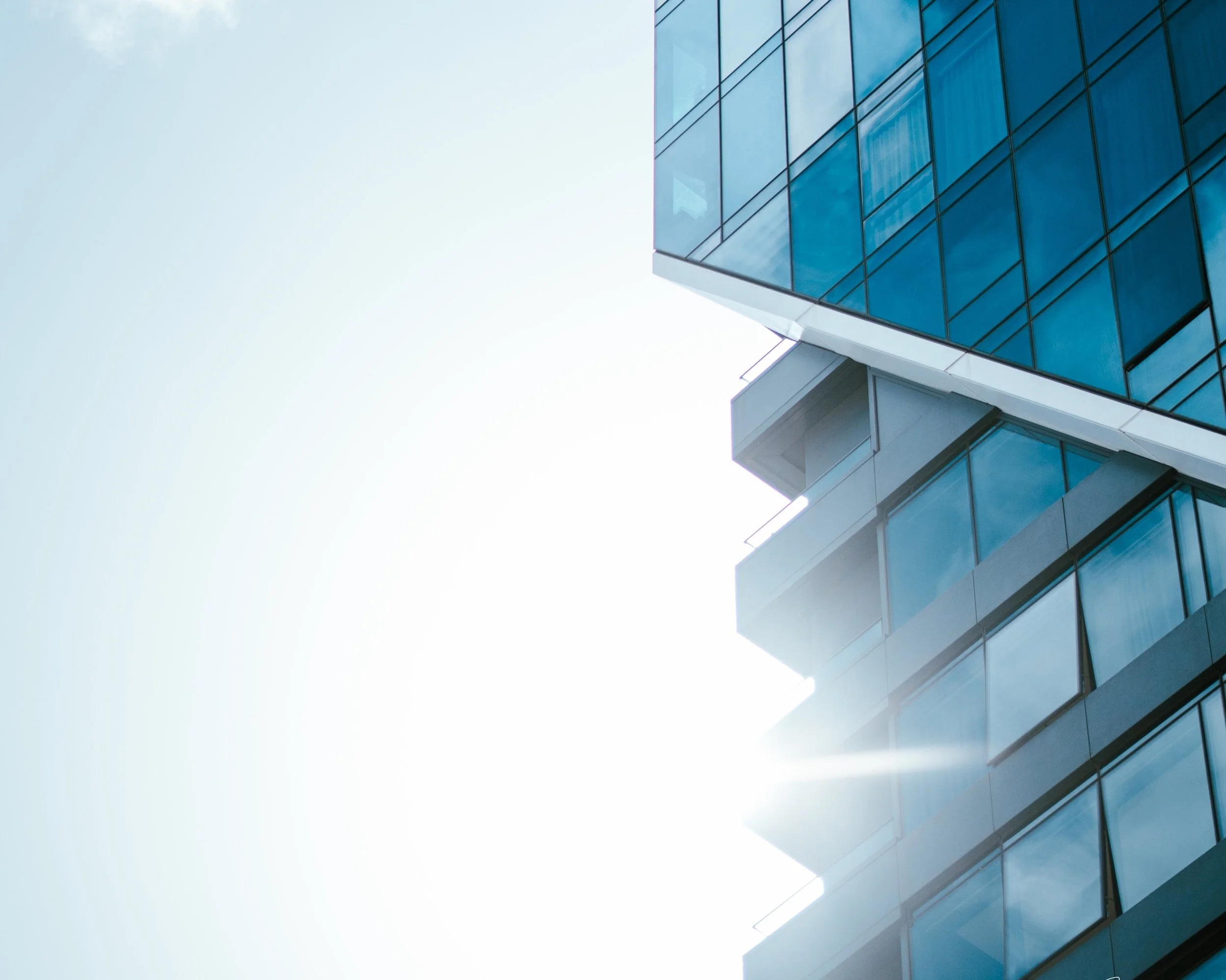 Modern glass building with reflective windows and a clear blue sky.