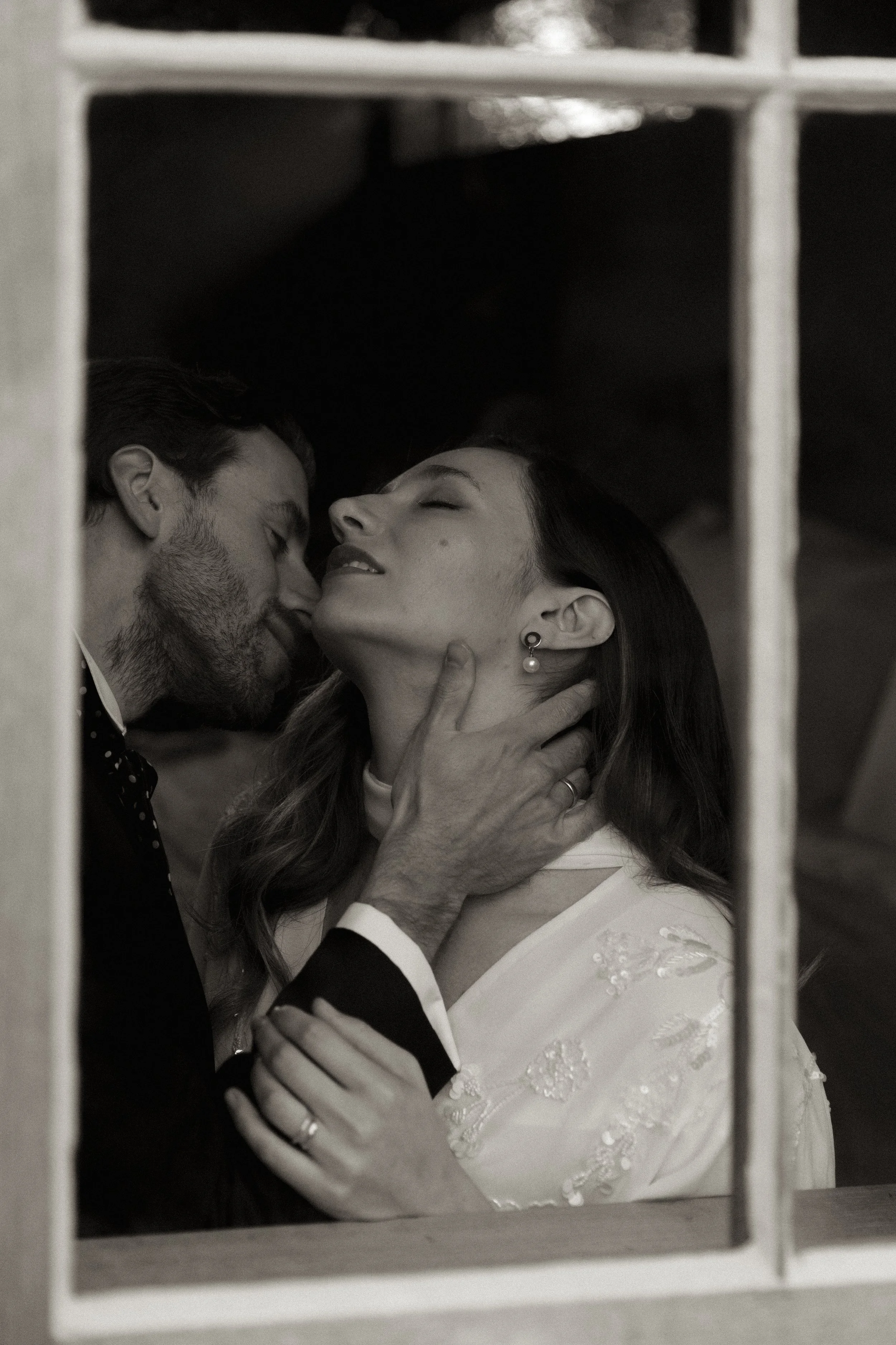 A couple kiss passionaltely , seen through a sash window