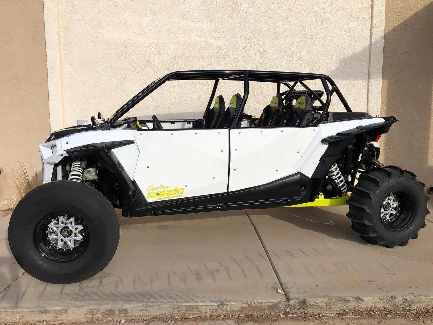 Off-road vehicle with four seats, large tires, and a black roll cage.